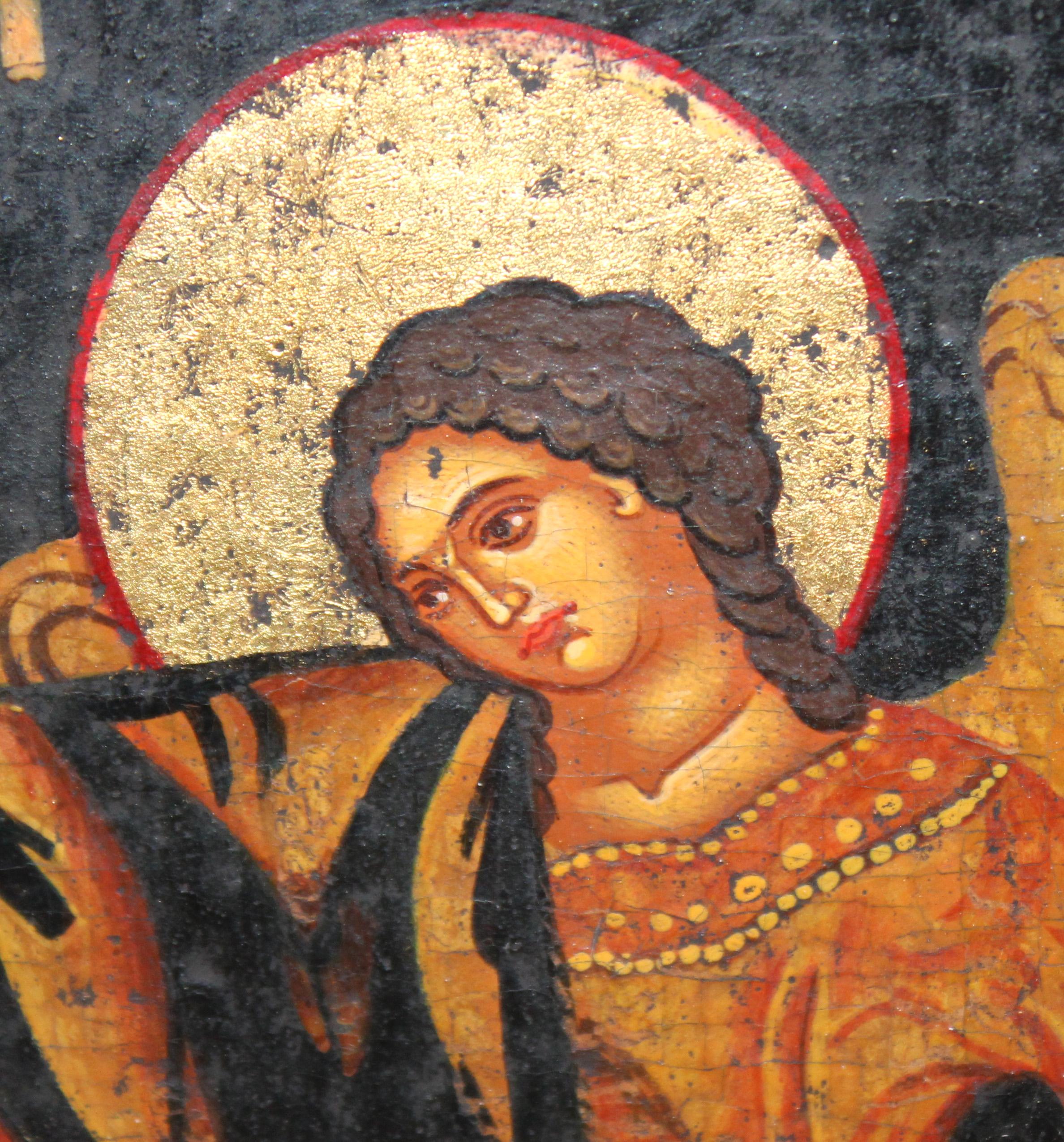Esta obra es un icono religioso de estilo bizantino, característico por su fondo dorado y la representación solemne de figuras sagradas. La escena central muestra a la Virgen María, vestida con un manto rojo y túnica azul, sosteniendo al Niño Jesús