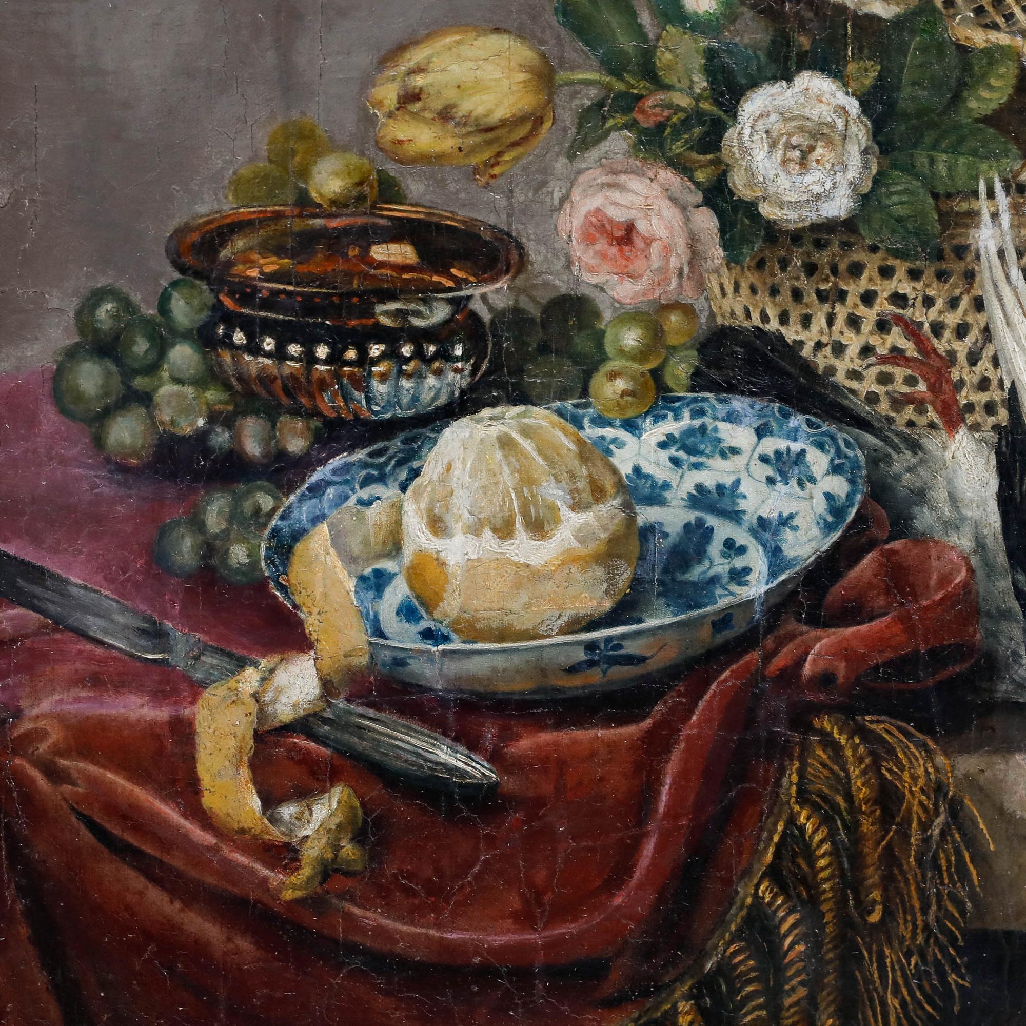 This elegant still life composition showcases a wicker basket filled with delicate roses and a single tulip, alongside a carefully peeled lemon, clusters of grapes, a glass vessel, and a dead pigeon. Indistinctly signed to the lower right corner.