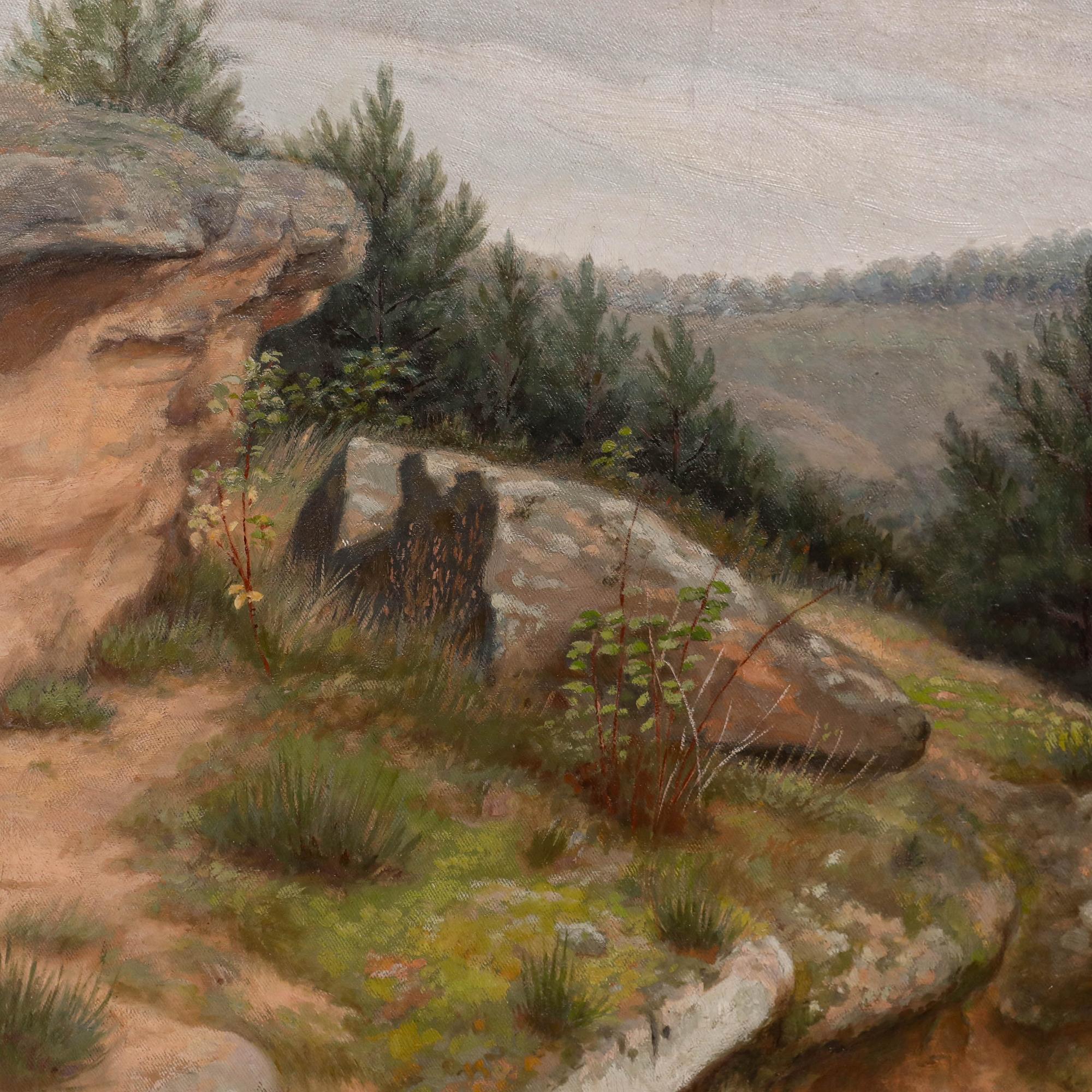 Eine zerklüftete Gebirgslandschaft mit verwitterten Felsen und robuster Vegetation im Vordergrund und mit Kiefern bewachsenen Hügeln in der Ferne. Präsentiert in einem Rahmen mit Goldeffekt. Auf einer am Rahmen angebrachten Plakette steht