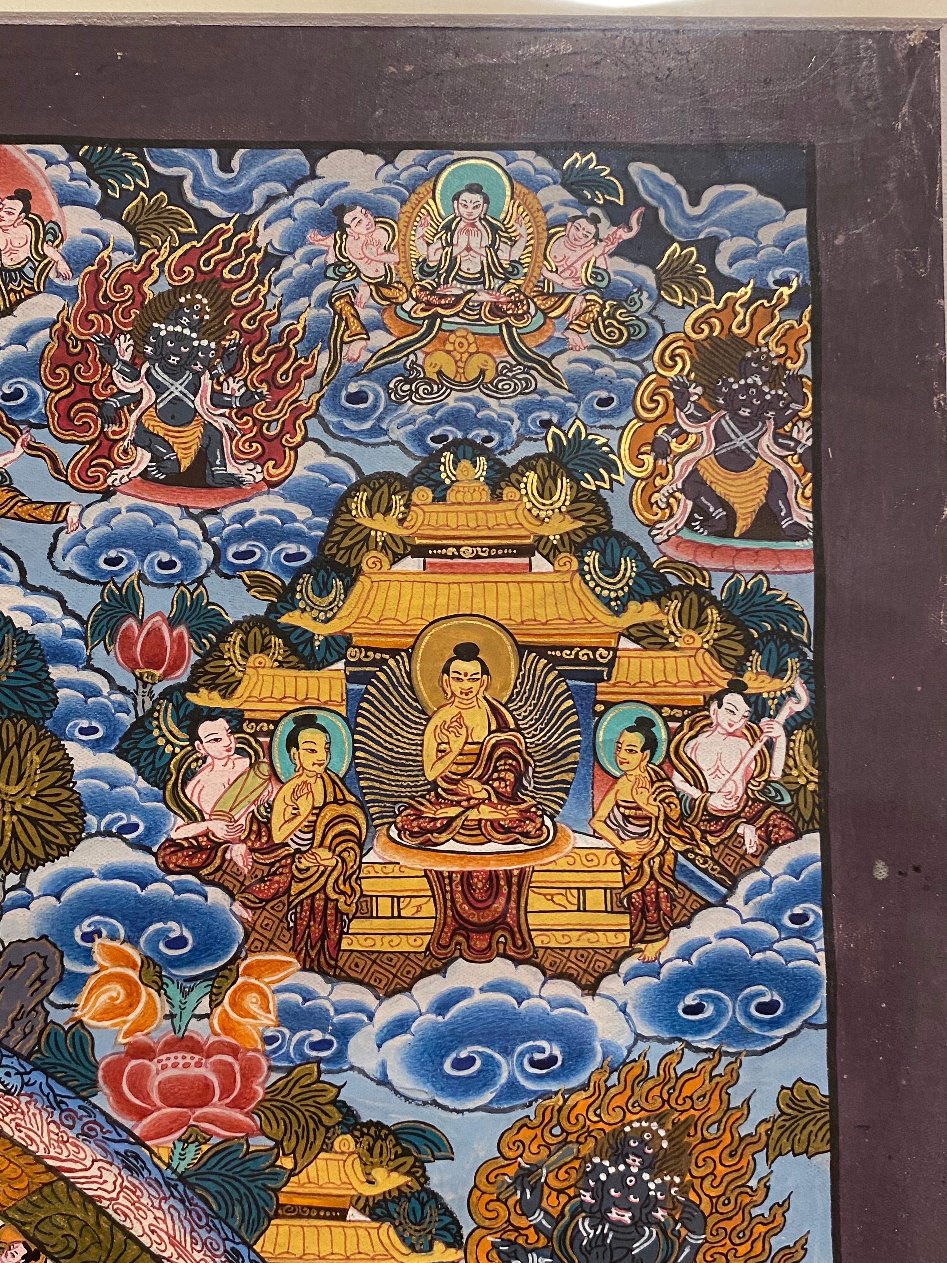 Este thangka mandala bellamente enmarcado está meticulosamente pintado a mano sobre lienzo, adornado con oro auténtico de 24 quilates. Los colores azul, ocre y  Los tonos verdes, complementados con el toque dorado, la convierten en una obra de arte