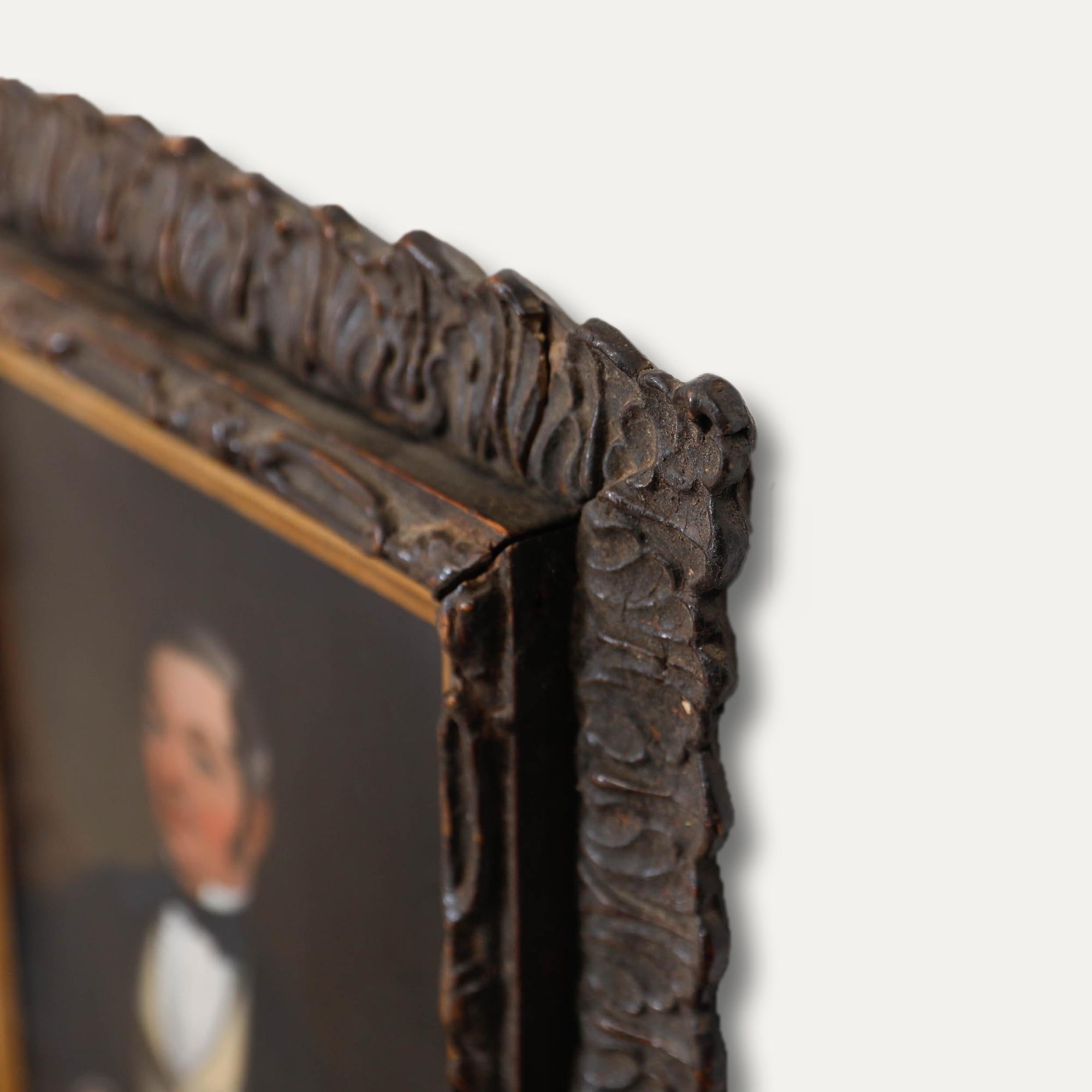 Un beau portrait de l'École continentale du XIXe siècle représentant un gentleman distingué vêtu d'une tenue formelle, sur un fond sombre. Le portrait est magnifiquement placé dans un cadre en bois orné de détails sculptés complexes, ce qui ajoute à
