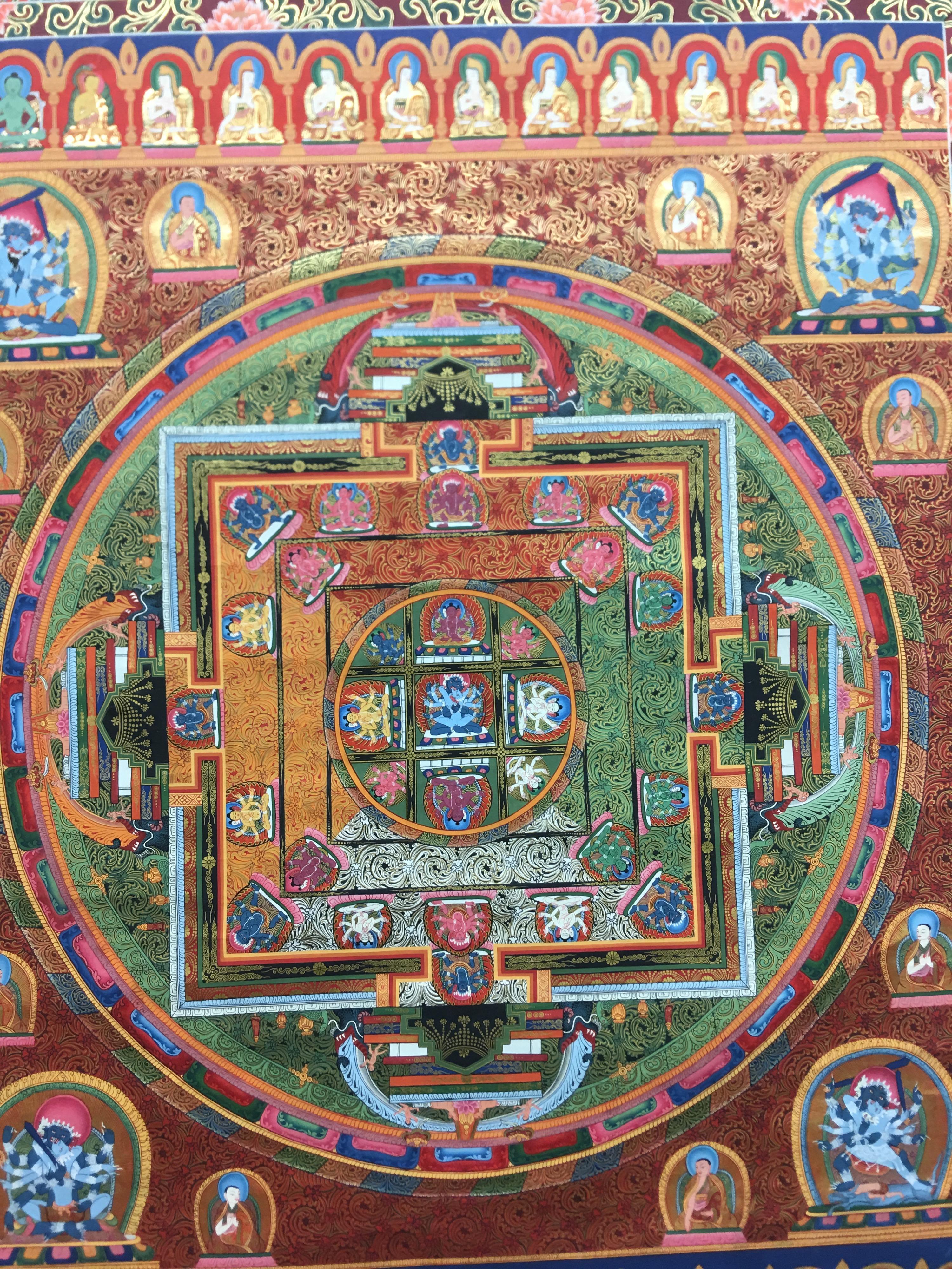 This mandala thangka is hand painted on canvas with 24k gold. Different hues of green,blue,red and orange colors blend seamlessly with the shimmering of real gold. 
Mandala means circle in Sanskrit. Mandala is a spiritual and ritual symbol in