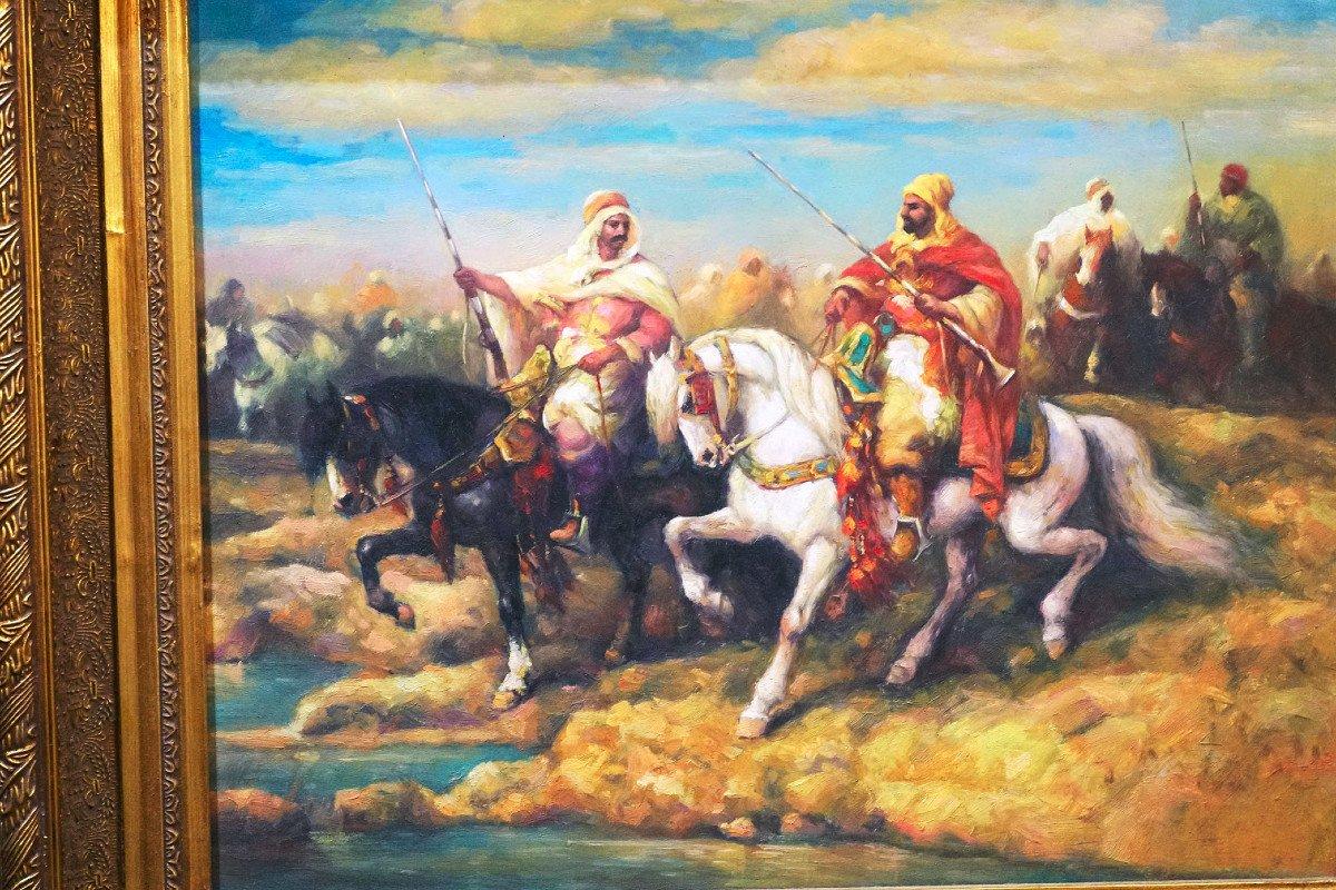 In diesem stimmungsvollen orientalischen Ölgemälde stehen zwei kriegslüsterne Ritter im Mittelpunkt eines stimmungsvollen Hintergrunds. Ein Ritter auf einem majestätischen weißen Pferd steht in starkem Kontrast zu seinem Gegenstück auf einem wilden