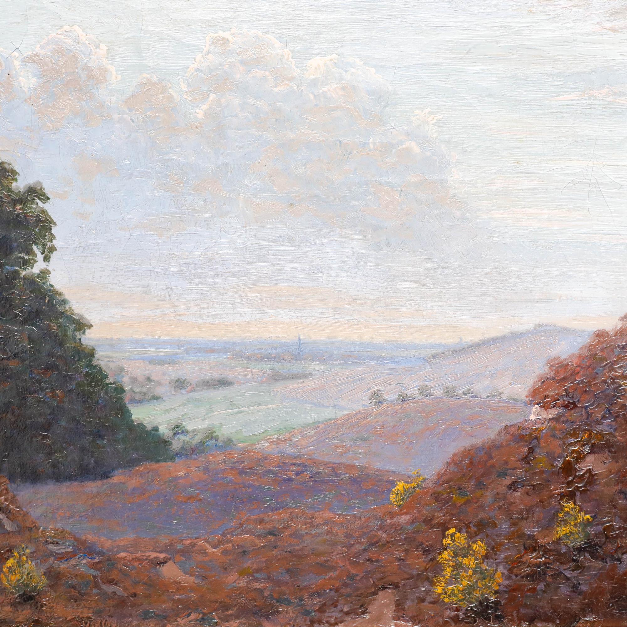 This landscape painting depicts a sweeping vista with rolling hills viewed from an elevated vantage point. Framed by darker foliage in the foreground, the composition draws the viewer's eye through the valley towards the town visible in the