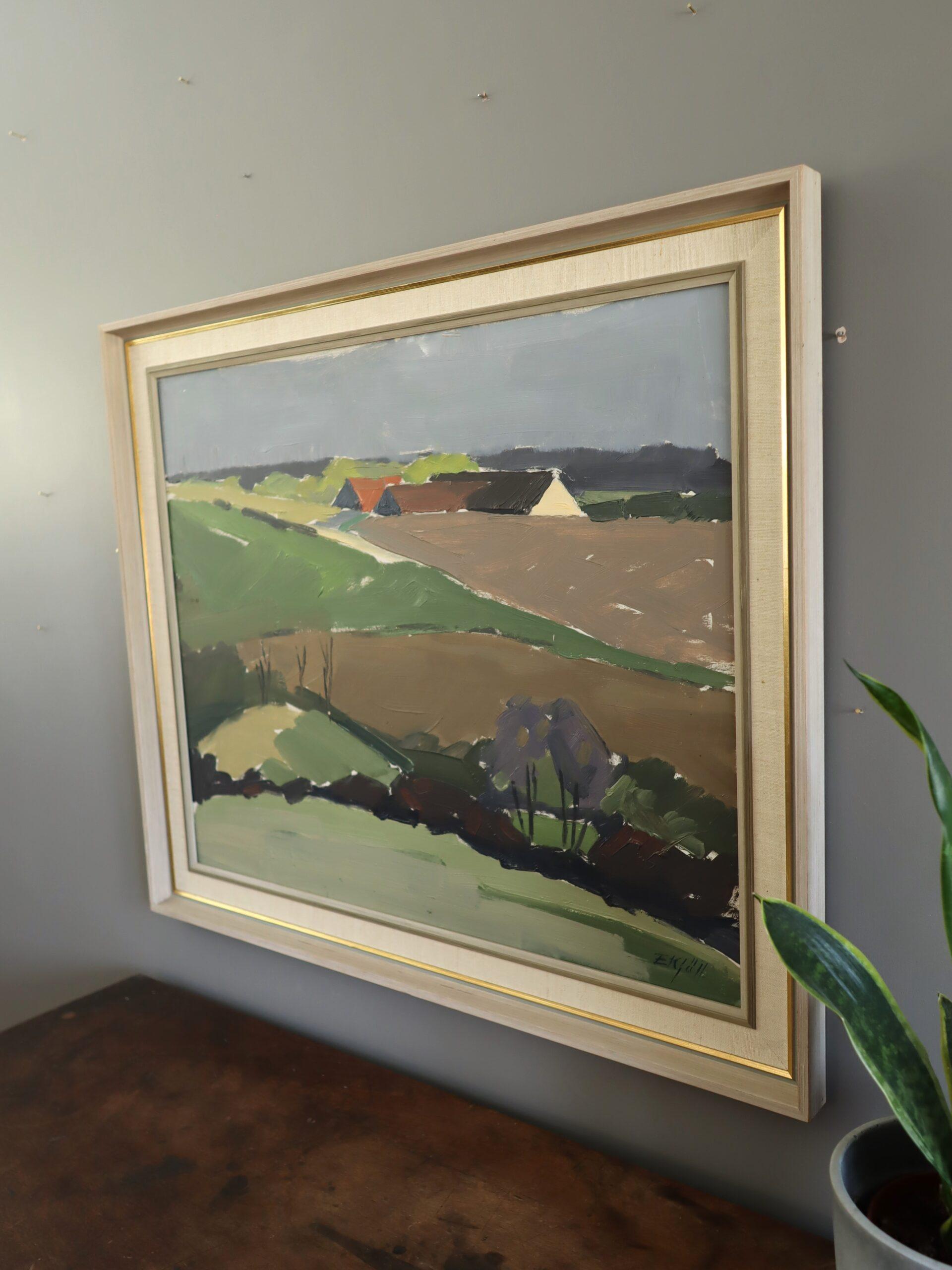 GEHÖFT AM HANG
Größe: 60 x 70,5 cm (einschließlich Rahmen)
Öl auf Karton

Eine modernistische Landschaft aus der Mitte des Jahrhunderts fängt eine ruhige und weite Szene ein, mit sanften Hügeln, die zu einer Ansammlung von landwirtschaftlichen