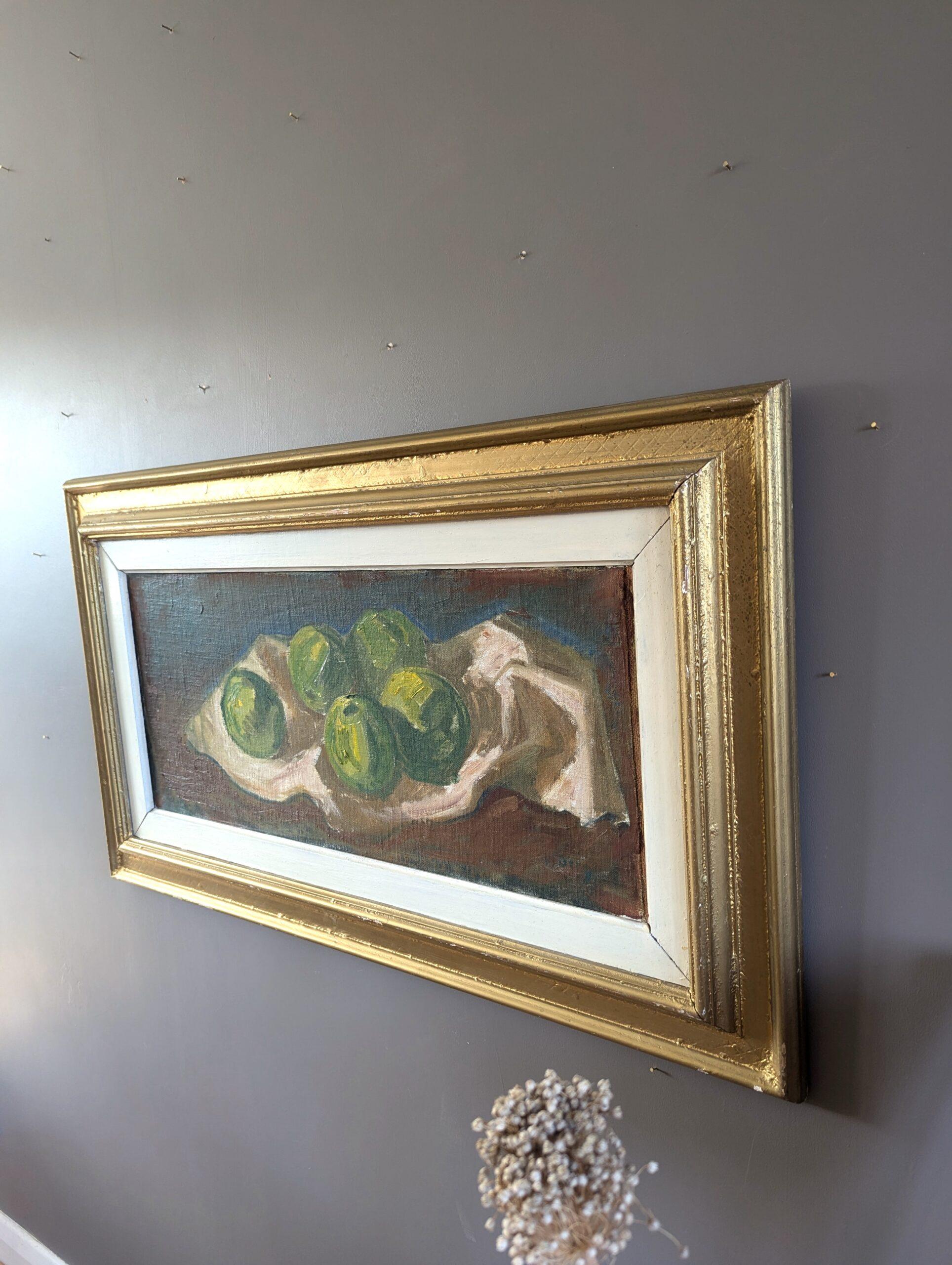 STILLLEBEN MIT GRÜNEN ÄPFELN
Größe: 49,5 x 85 cm (einschließlich Rahmen)
Öl auf Karton

Das große und ausdrucksstarke Stillleben aus der Mitte des Jahrhunderts zeigt ein einfaches, aber wirkungsvolles Arrangement aus grünen Äpfeln, die auf einem