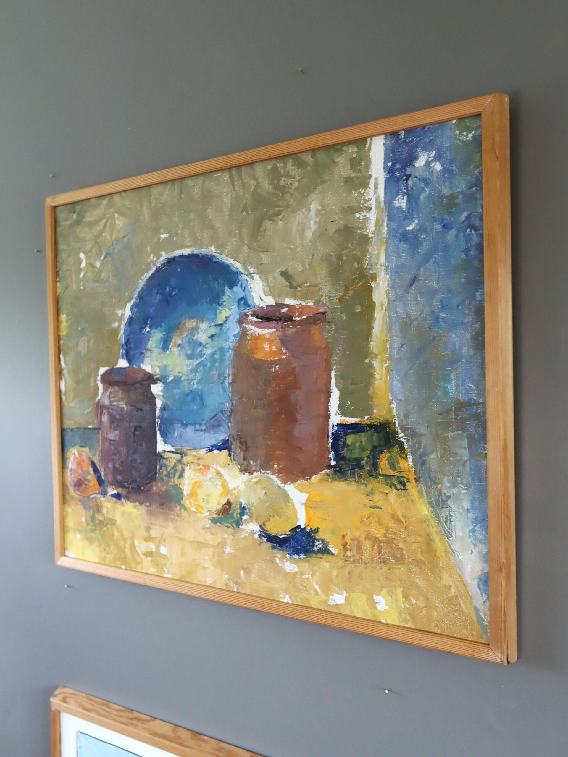 GLÄSER & BLAUER TELLER
Größe: 57 x 68,5 cm (einschließlich Rahmen)
Öl auf Leinwand

Ein lebhaftes Stillleben aus der Mitte des Jahrhunderts zeigt ein ruhiges, alltägliches Arrangement aus zwei Steingutgläsern, einem kobaltblauen Teller und ein paar