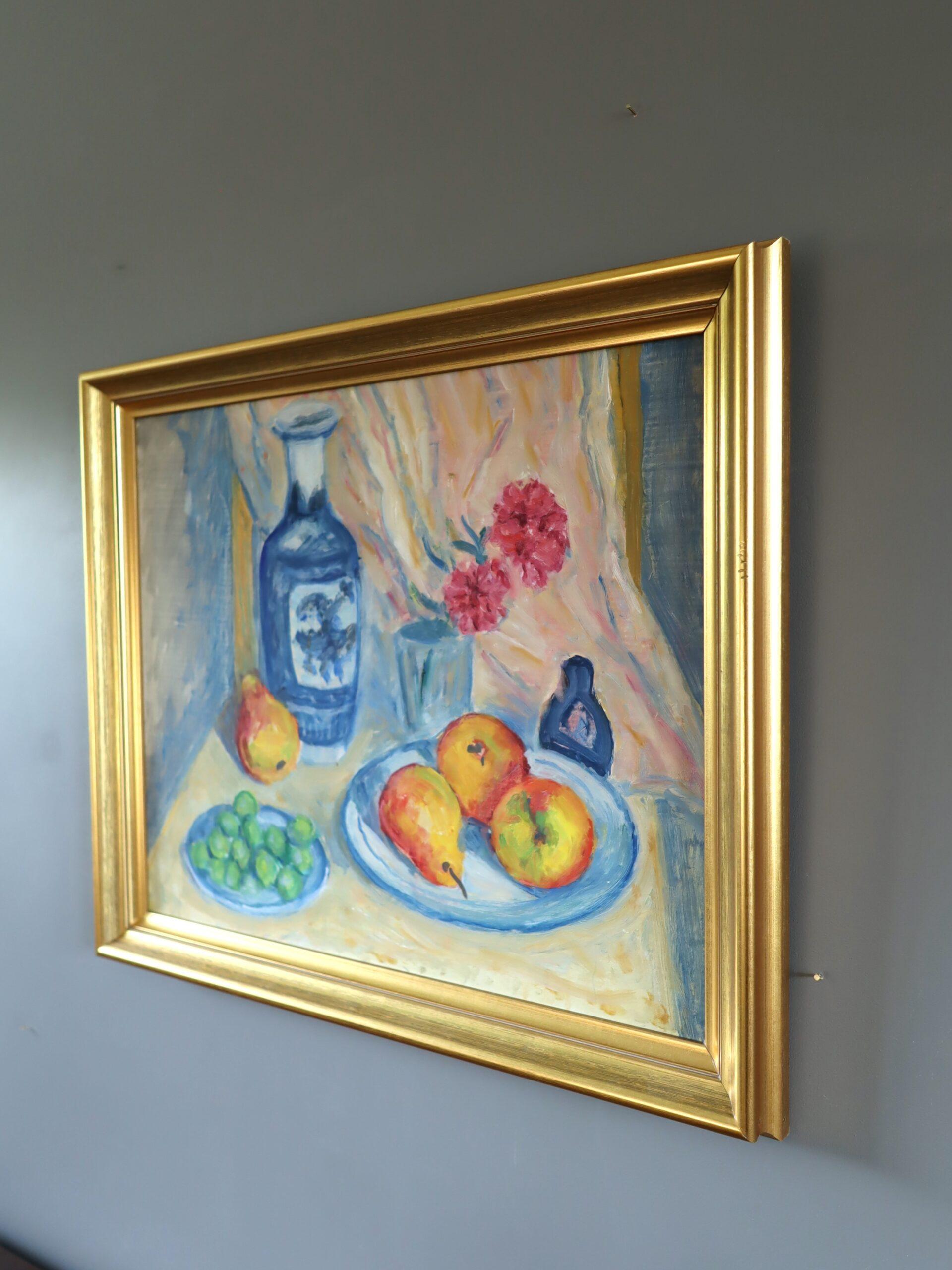 FRUITS ET VASE SUR UNE TABLE
Dimensions : 44,5 x 52,5 cm (cadre compris)
Huile sur carton

Cette nature morte énergique du milieu du siècle présente un arrangement vivant d'objets quotidiens, avec des contrastes de couleurs audacieux et un coup de