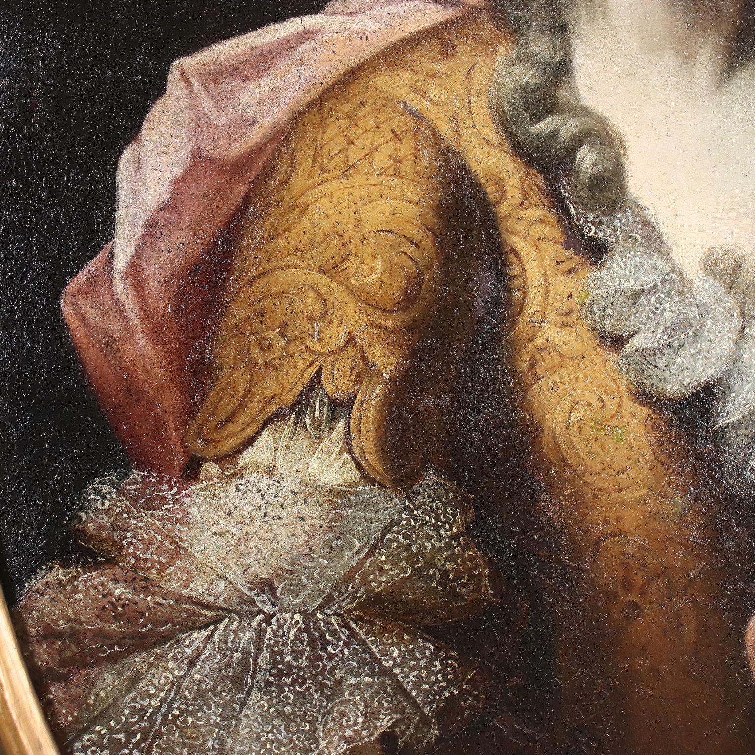 Oil painting on canvas. Lombard school. The oval portrait of the noblewoman highlights the richness of the damask corset and delicate lace but also the severe hairstyle and the rigid composure of the look and pose; the lady drapes a red cloak around