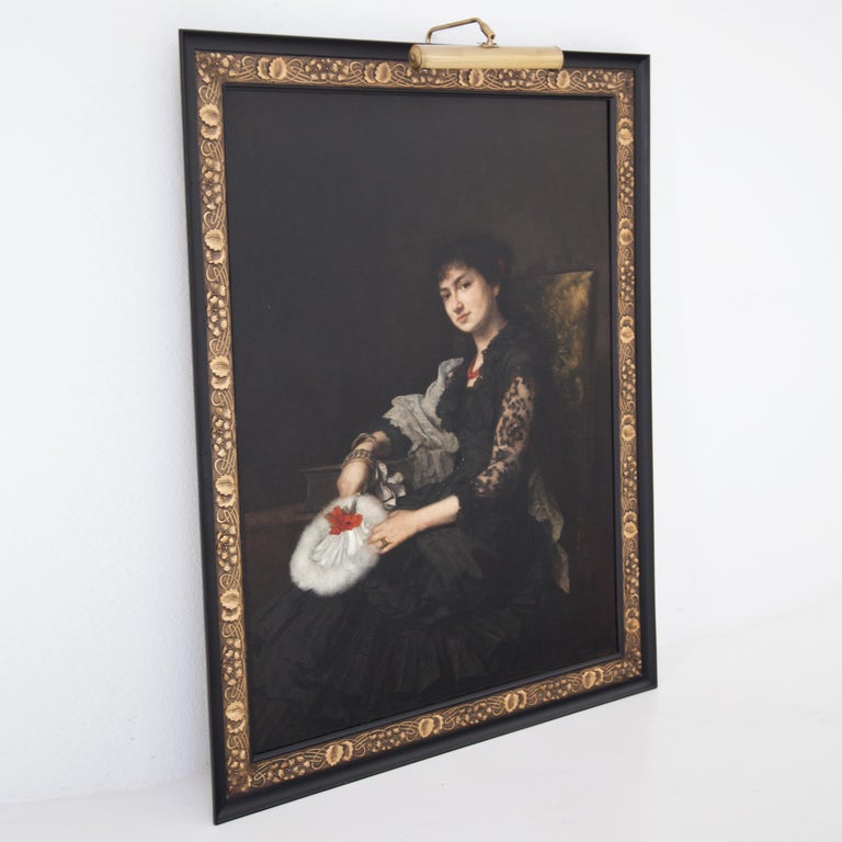 Large-format three-quarter portrait of a sitting young lady in a black dress with a wide crinoline skirt; the sleeves and collar are made of black lace. A red pearl necklace and a white feather fan with a small bouquet of carnations stand out from