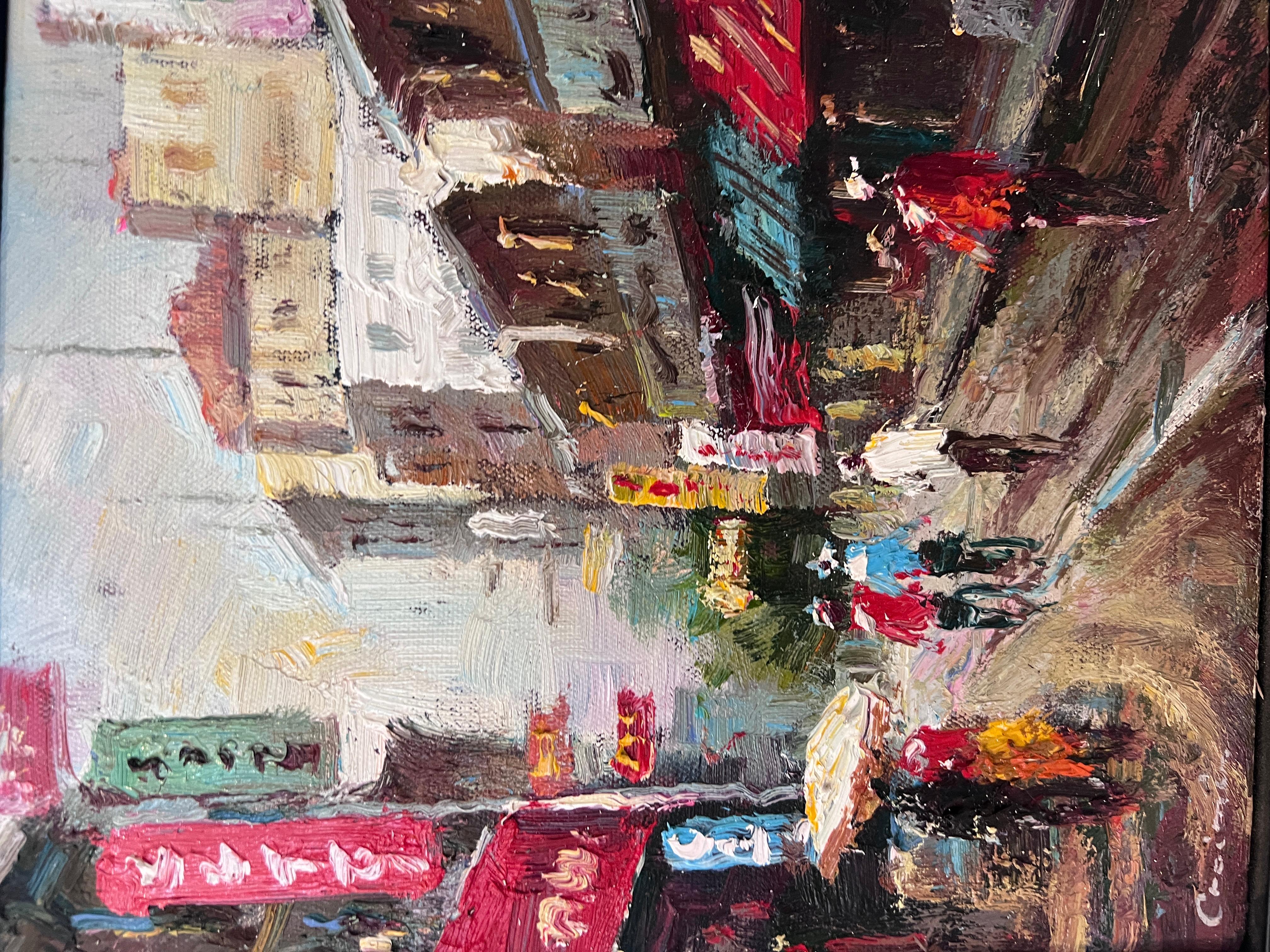 A vibrant small oil painting on canvas featuring a lively street scene rendered in thick, expressive impasto. The artist captures the movement and energy of pedestrians, cyclists, and storefronts with bold palette-knife strokes and rich color