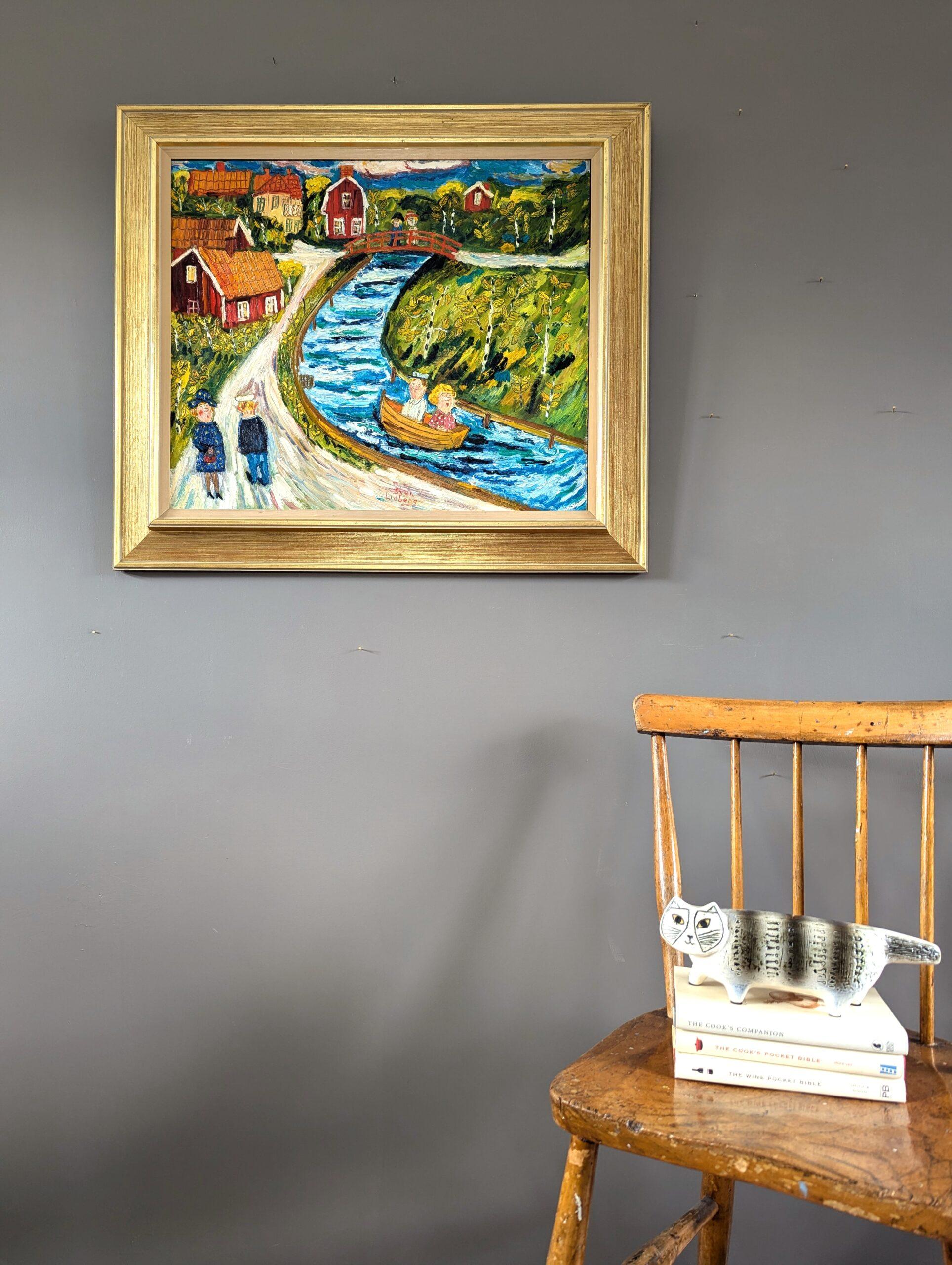 DOWN RIVER
Oil on Board
Size: 61.5 x 70.5 cm (including frame)

A vibrant and playful Naïve style composition of a riverside scene, executed in oil  onto board.

This narrative painting presents a river winding through the center of the composition.