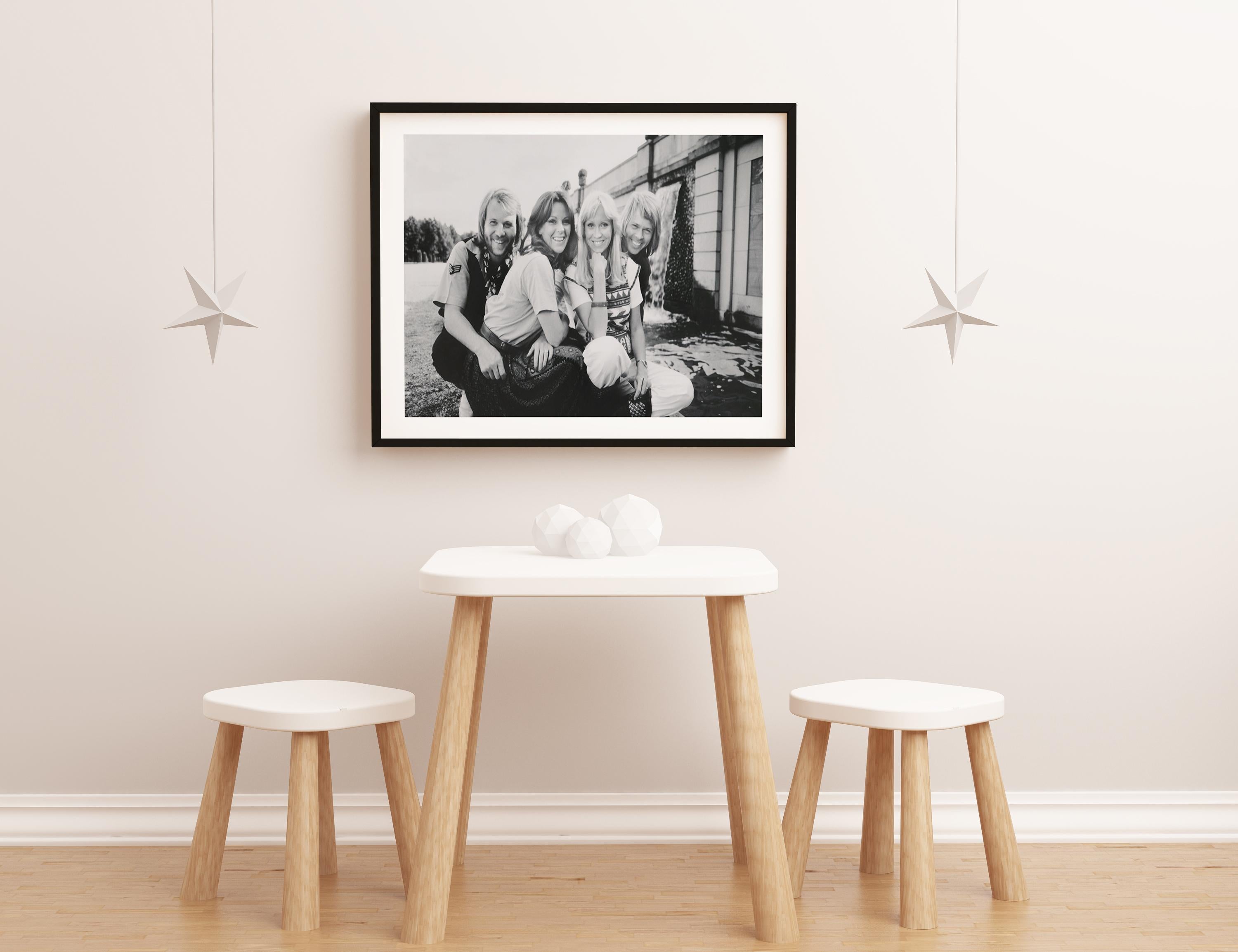 This black and white group portrait features members of the band ABBA (Agnetha Fältskog, Björn Ulvaeus, Benny Andersson, and Anni-Frid Lyngstad) sitting outdoors, smiling together.

ABBA is a Swedish pop group formed in Stockholm in 1972. The