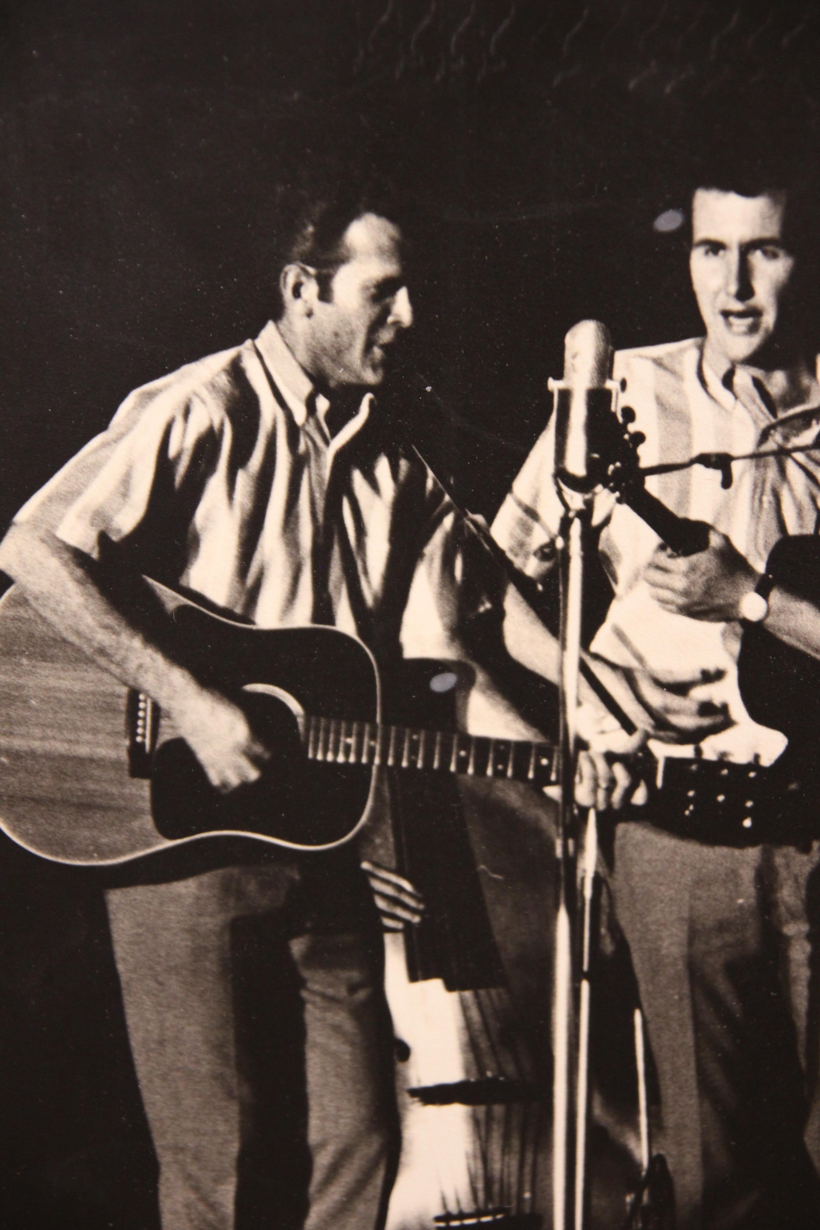 Photographie en noir et blanc du groupe de musique folk et pop américain emblématique qui a vu le jour entre la fin des années 1950 et la fin des années 1960. La photographie n'est pas encadrée mais est attachée à un panneau. 