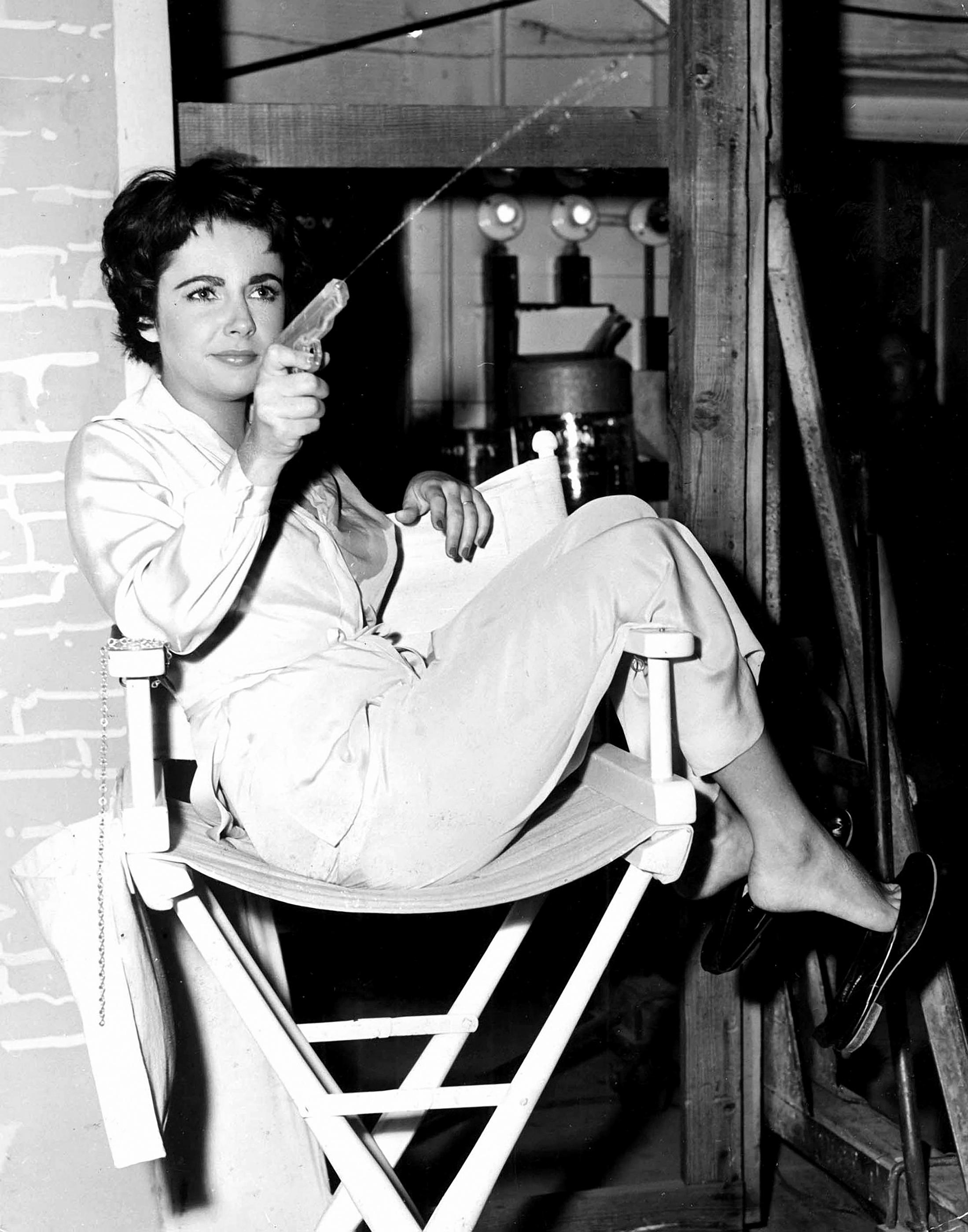 Liz A. Taylor schießt mit der Wasserpistole am Set – Photograph von Unknown