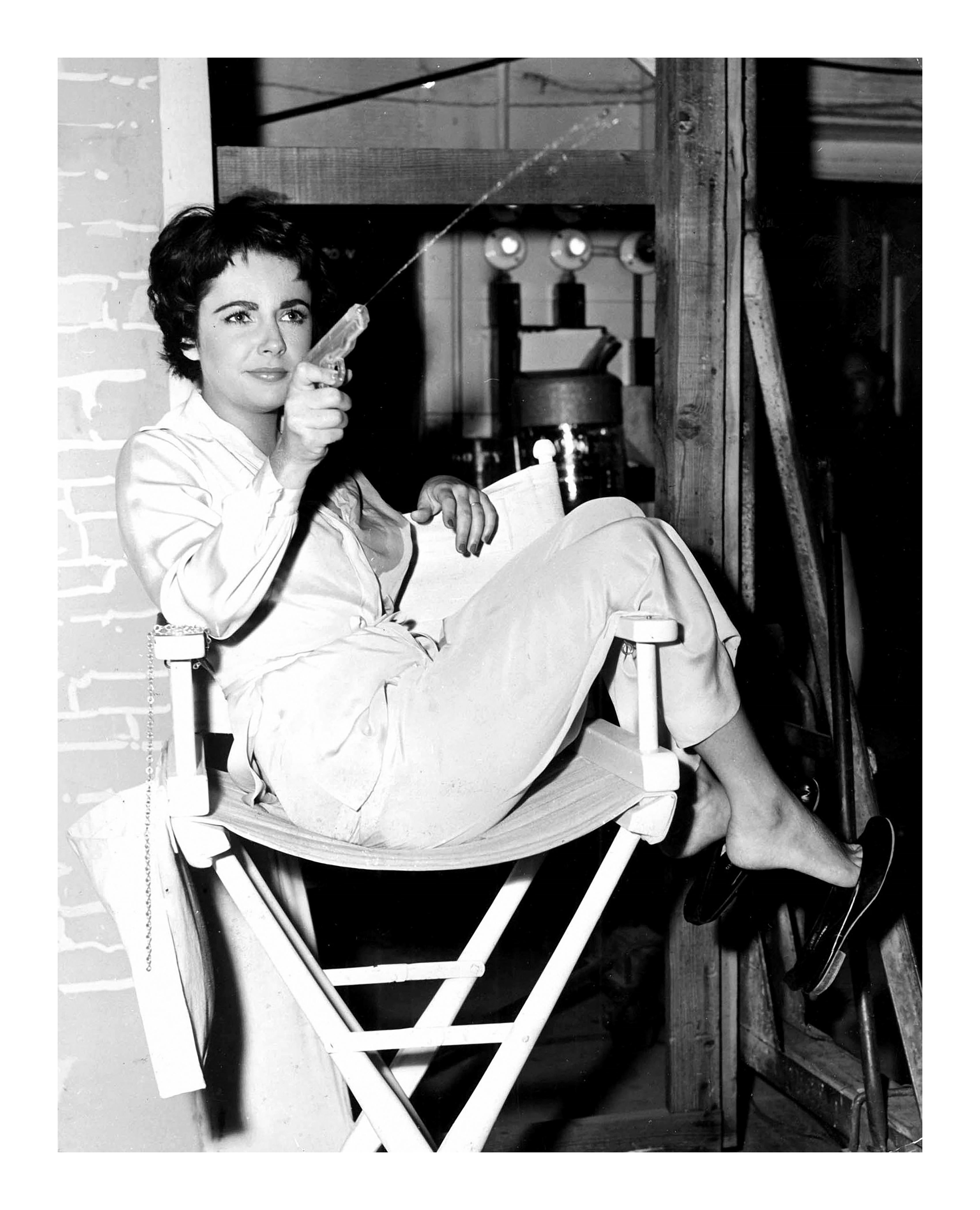 Liz A. Taylor schießt mit der Wasserpistole am Set (Zeitgenössisch), Photograph, von Unknown
