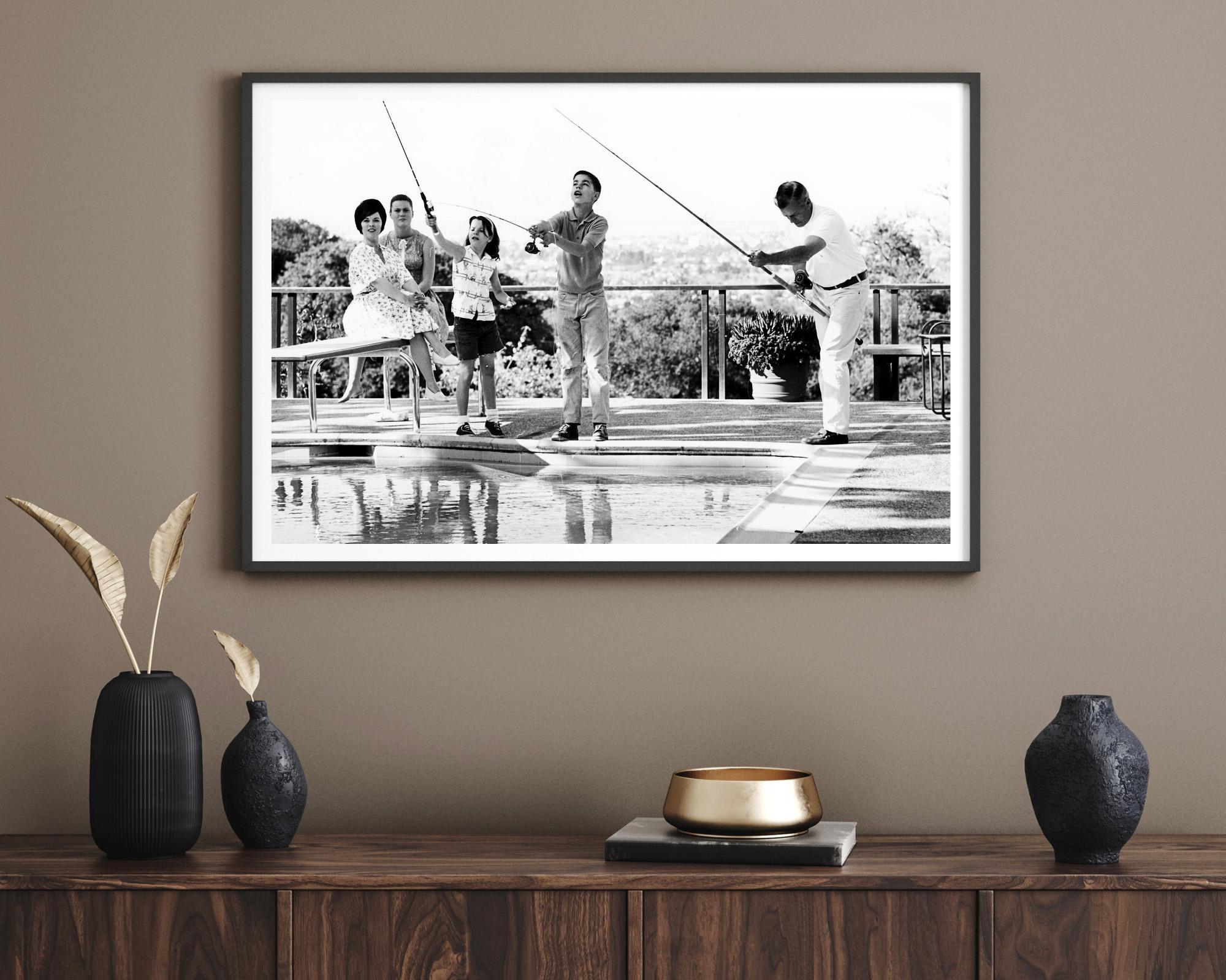 Cette photo en noir et blanc représente Shirley Temple en train de pêcher dans une piscine avec sa famille.

Shirley Temple était une enfant star américaine des années 1930 dont le charisme a illuminé de nombreux films de l'époque de la Dépression.