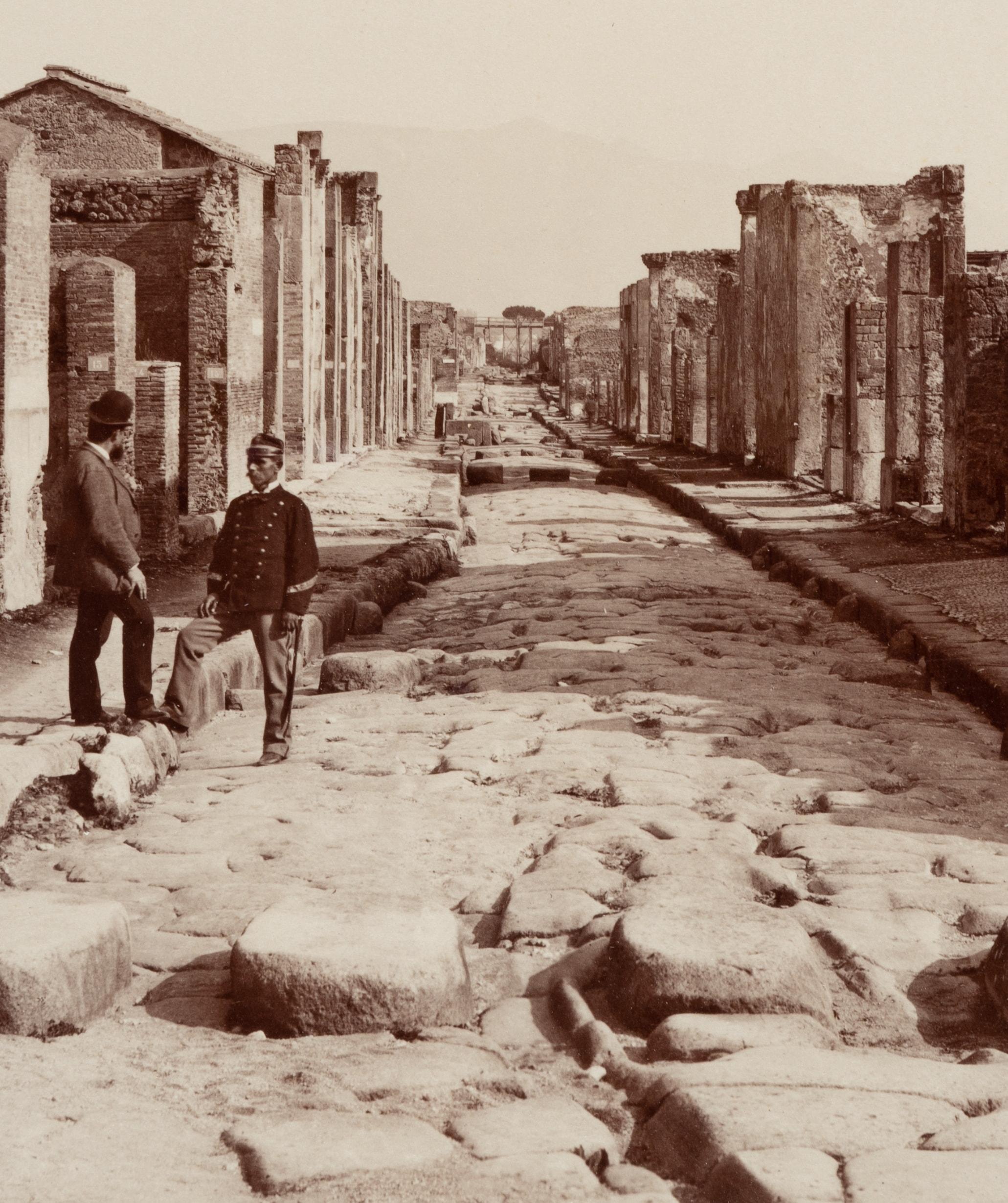 Fratelli Alinari (19th century): Pompei Strada della Fortuna View through one of the main streets of Pompei with two gentlemen placed by the photographer standing in the street, c. 1880, albumen paper print

Technique: albumen paper