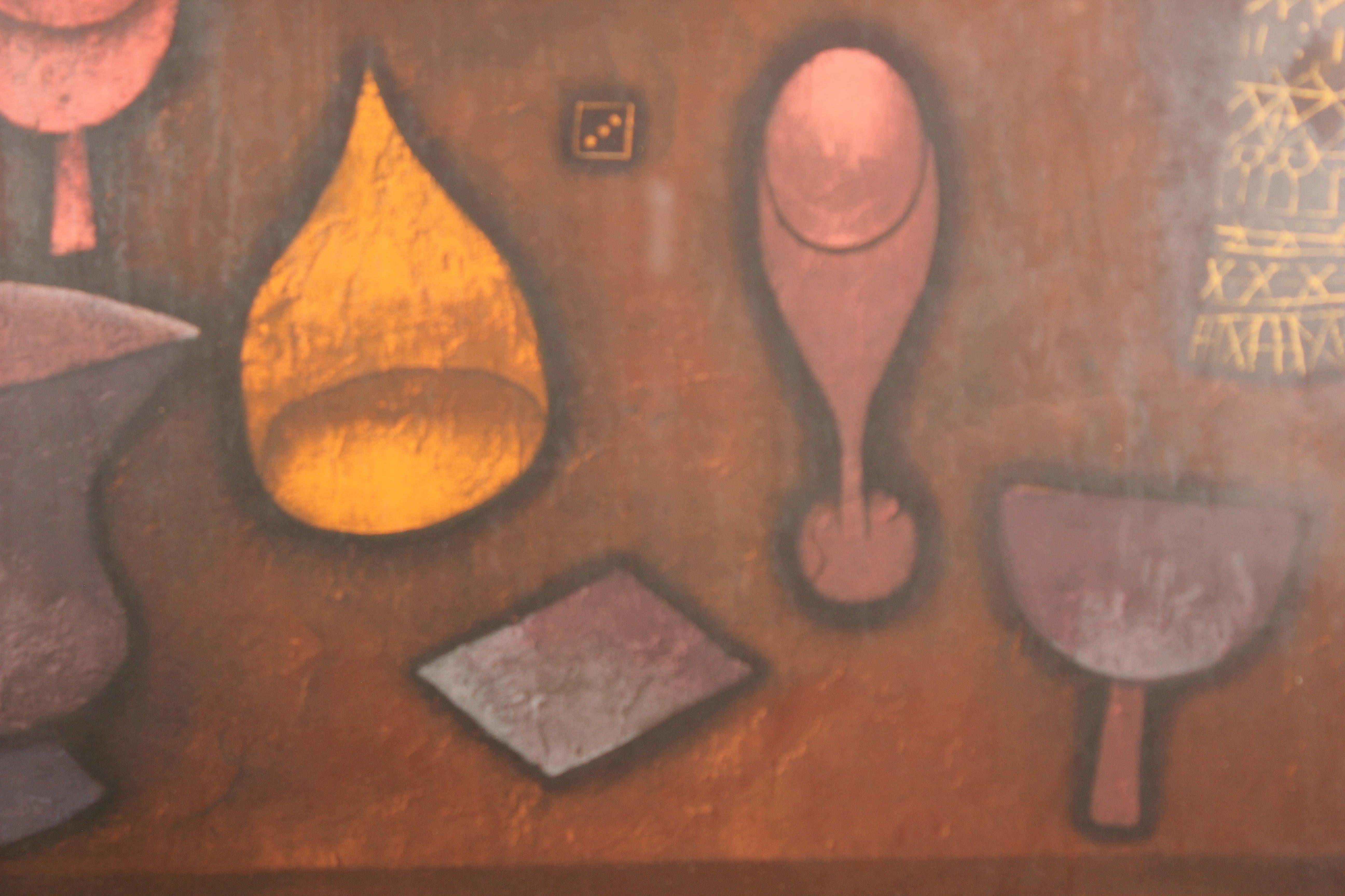 Deep tonal still life of things on a table top. The work consists of deep browns, blues, purples, oranges, and yellows. It is not signed but given an edition number. It is framed in a brown frame. The corner of the glass is cracked. There is a