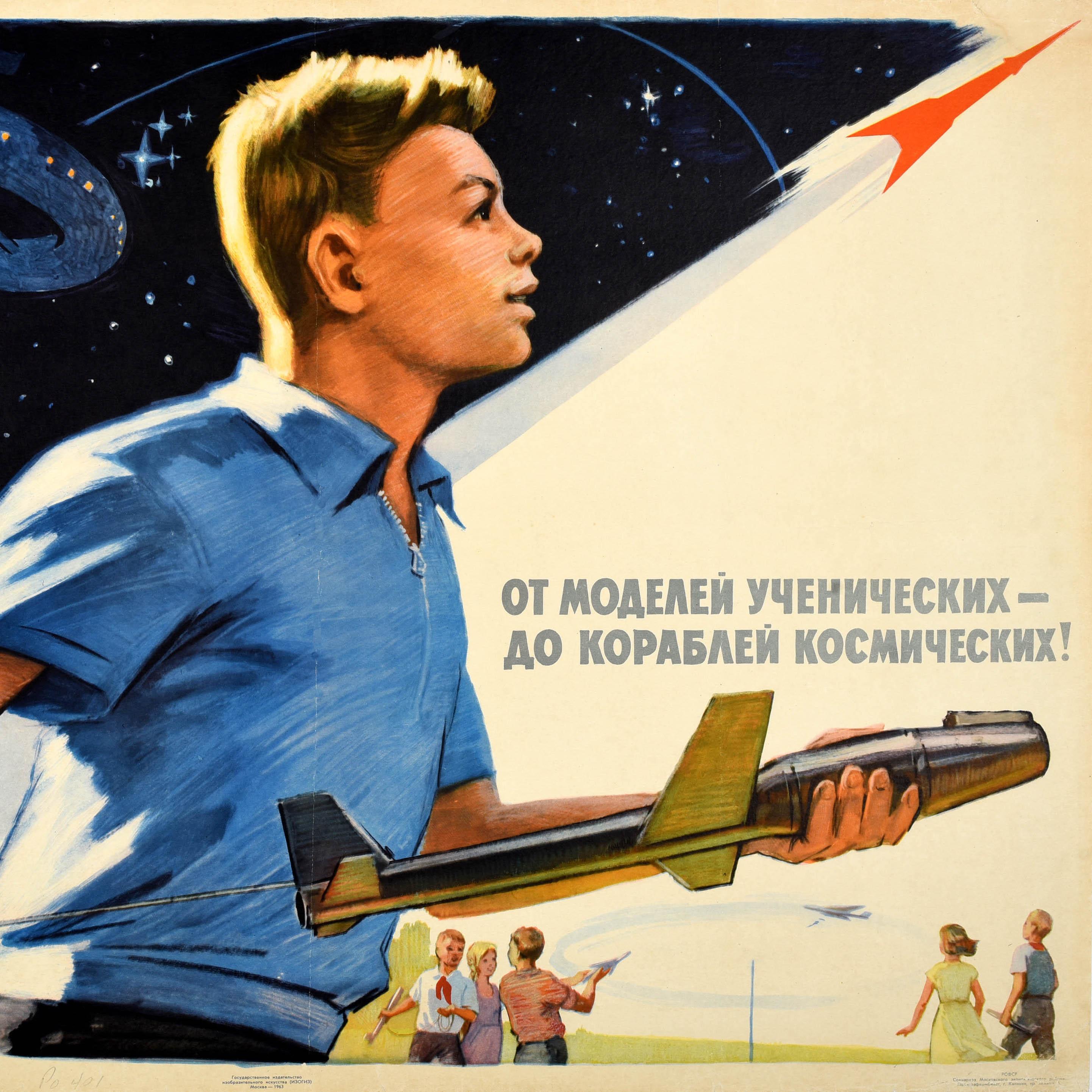 Affiche de propagande soviétique d'époque - Des maquettes d'étudiants aux vaisseaux spatiaux / От Моделей Ученических До Кораблей Космических ! - représentant un jeune garçon tirant sur la corde d'un modèle réduit de vaisseau spatial et regardant