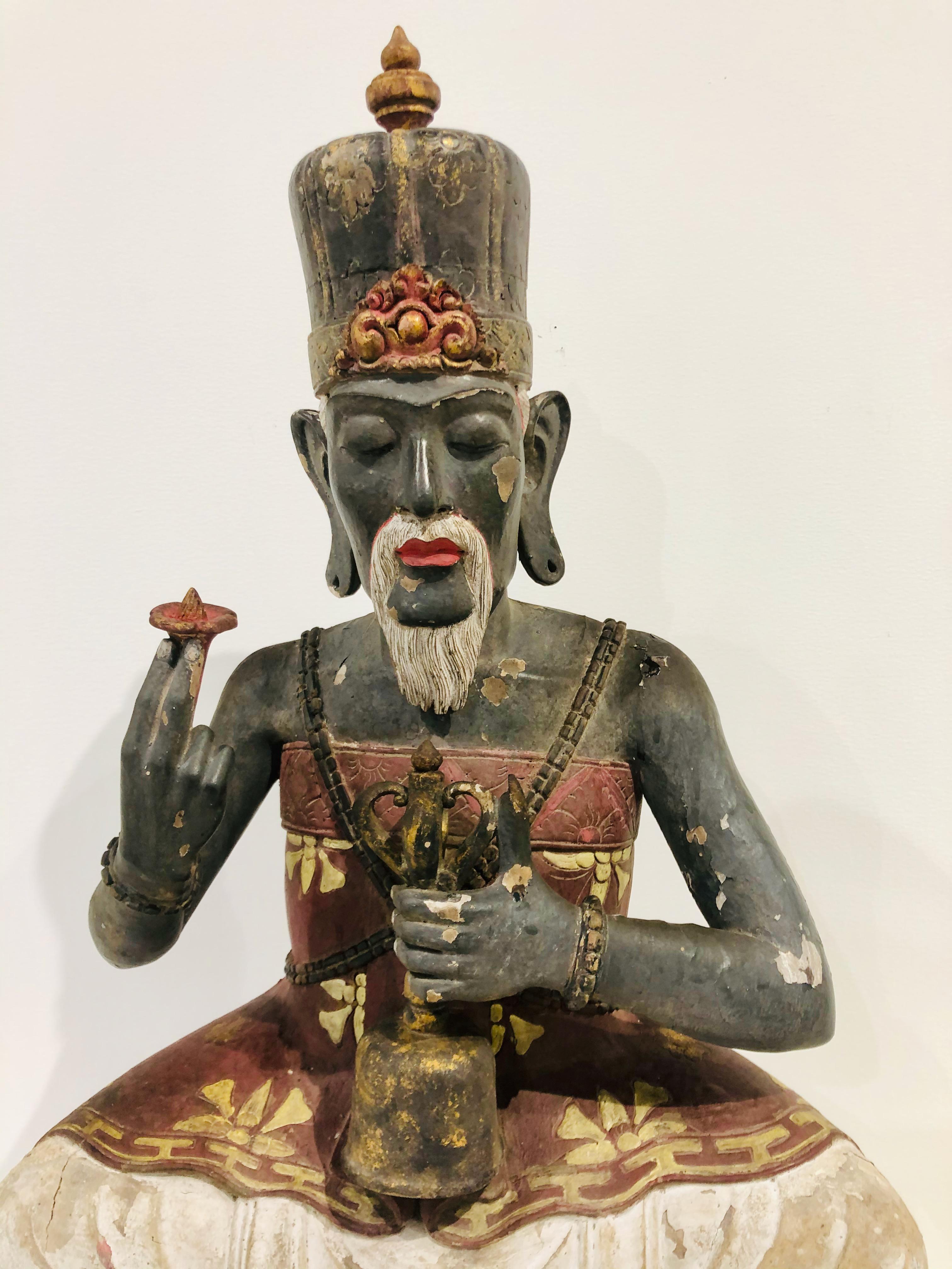 Buddhistischer Hohepriester in sitzender Position auf einer Lotusblume, 
 Polychrome Holzskulptur 
 Seltene balinesische Holzskulptur des buddhistischen Hohepriesters mit Blume und Gebetsglocke aus dem frühen 19. Jahrhundert. Handgeschnitztes