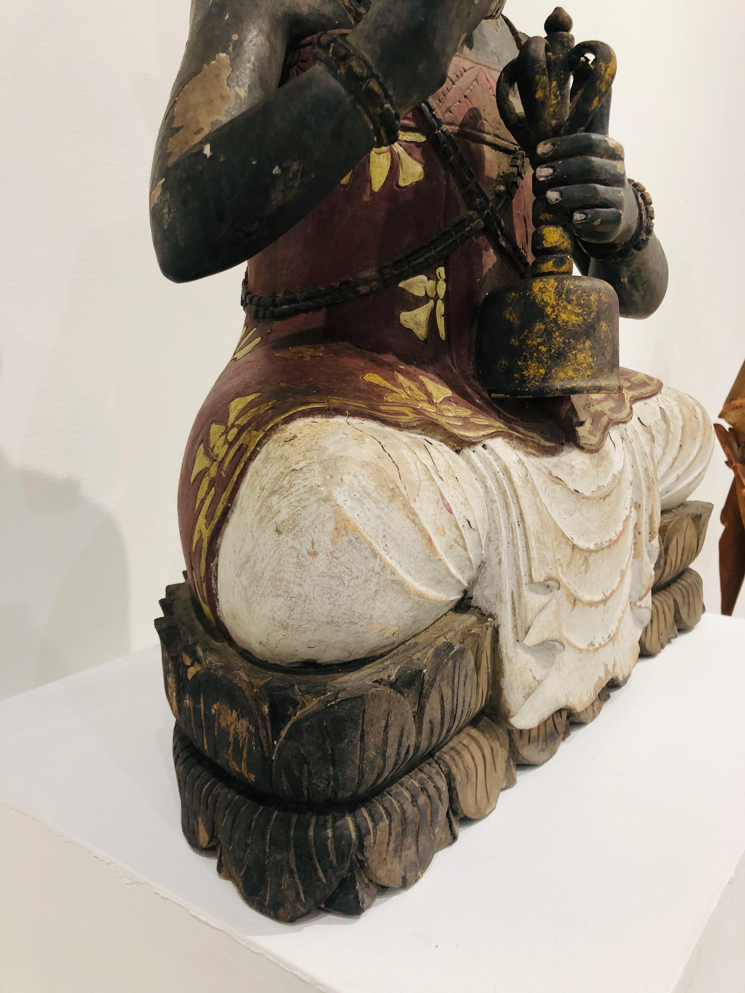 Buddhist High Priest in sitting position on lotus flower, 
 Polychrome Wood Sculpture 
 Rare early 19th-Century Balinese wood sculpture of the Buddhist High Priest holding flower and prayer bell. Hand carved Jackfruit wood with original polychrome