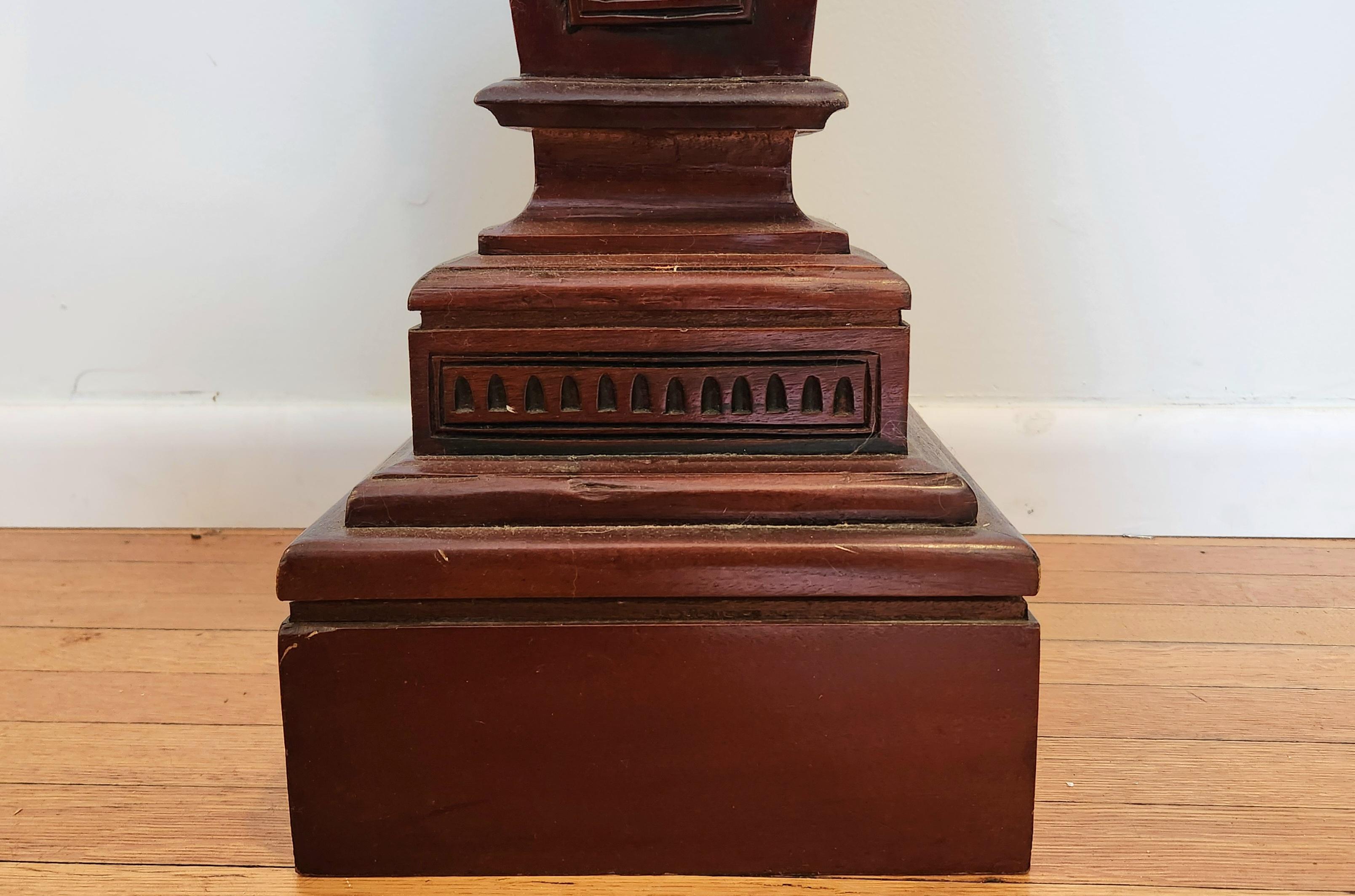 This beautiful mahogany pedestal is a wonderful example of the neoclassical style. It has detailed carvings of draped tapestries that are set in frames along the edges at the top of the piece. Further down are small flowers that decorate the top