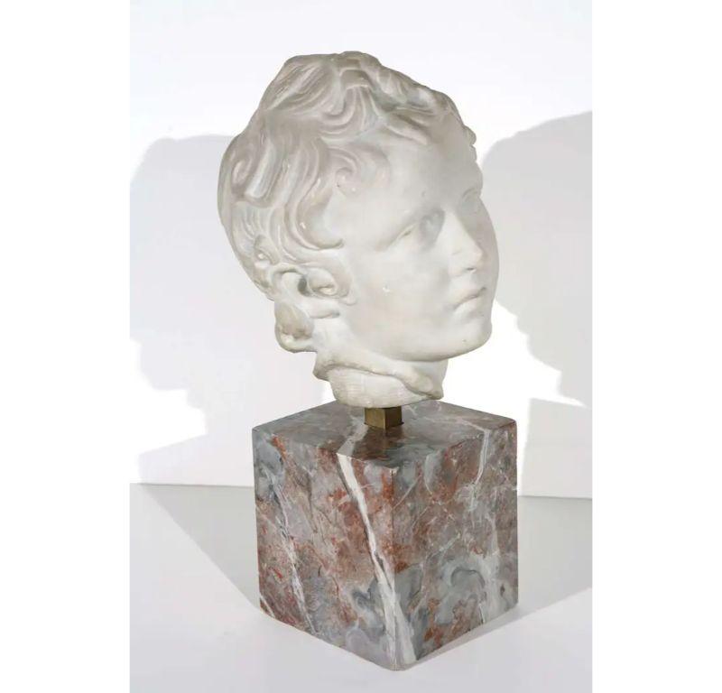 Une belle composition  Buste d'un jeune homme aux cheveux longs. Monté sur un socle en faux marbre peint à la main.