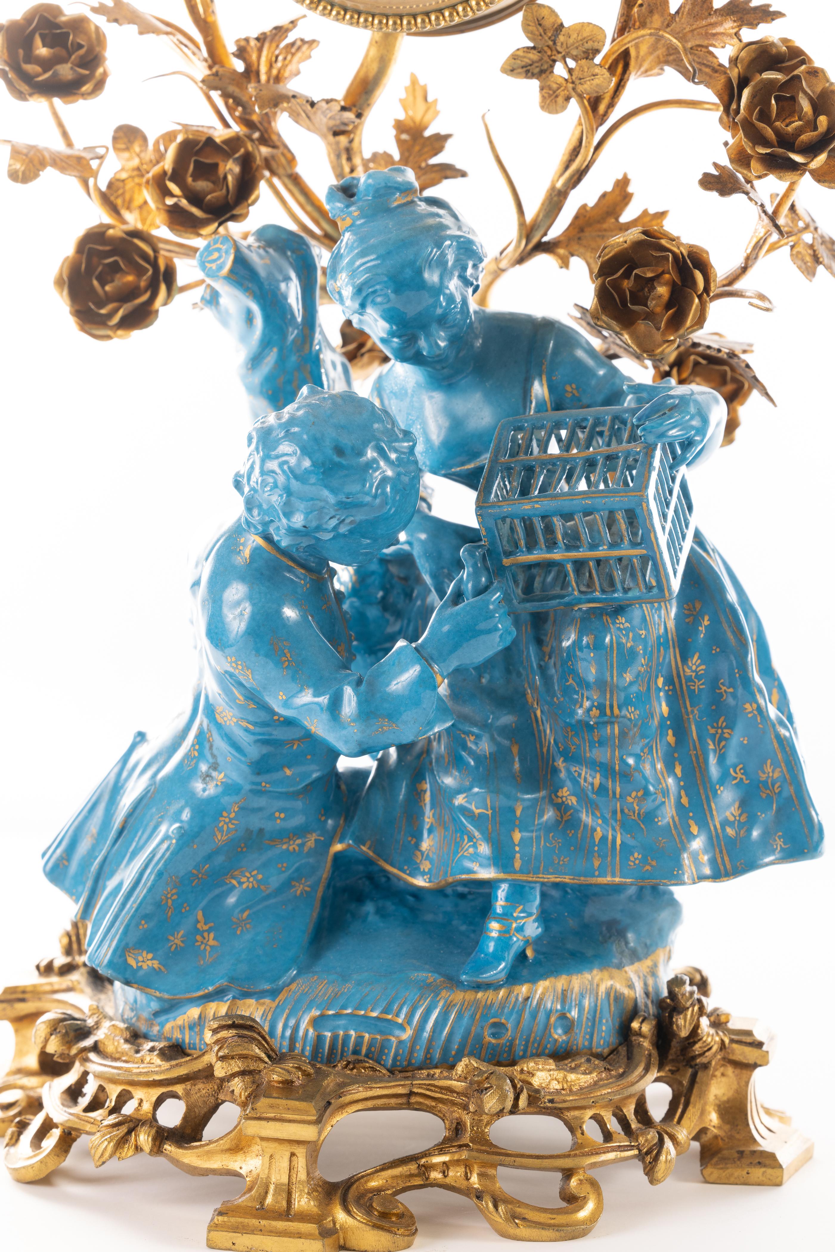 Elegante französische Uhr aus dem 19. Jahrhundert mit vergoldeten türkisfarbenen Porzellanfiguren eines jungen Mannes und einer Frau mit einem eingesperrten Vogel. Die Porzellanfigur ist in gutem Zustand, alle Finger sind intakt. Das Porzellan ist