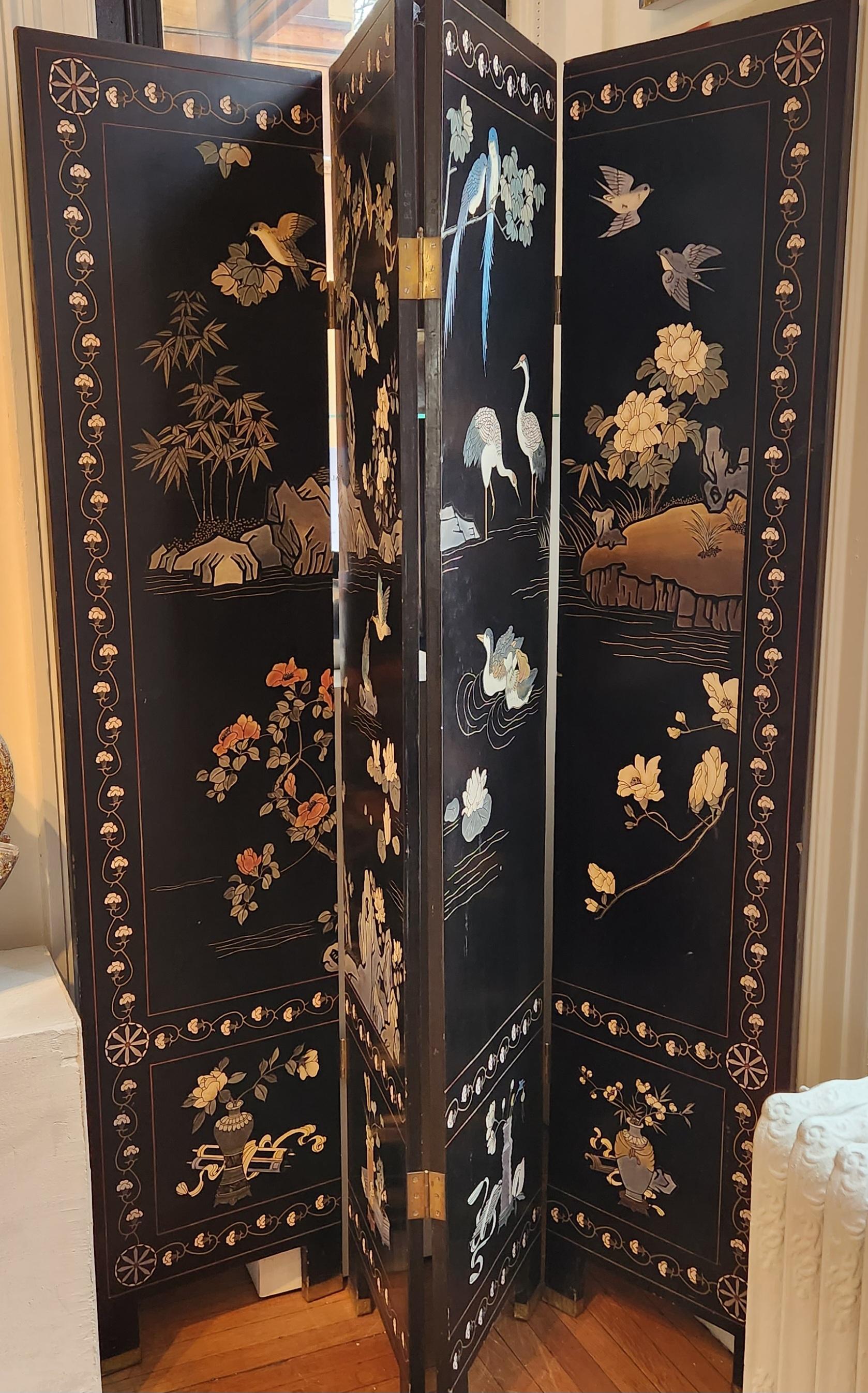 This 20th century lacquered Chinese screen is a wonderful example of hand carved work. There are three panels each with beautifully illustrated scenes of flora and fauna. The panels are lined with rows of white flower engravings that separate