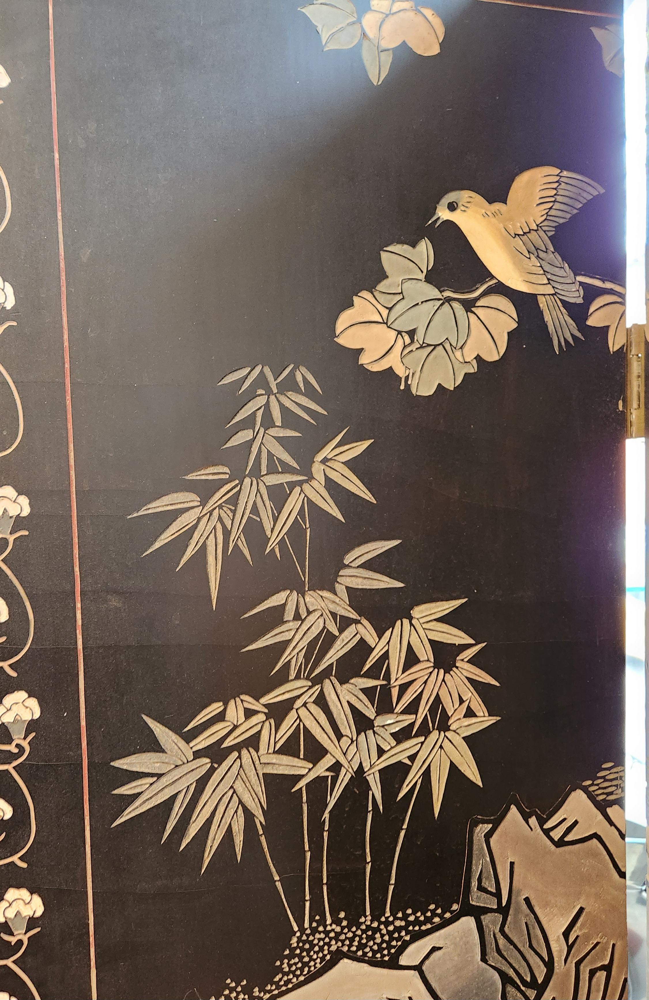 Ce paravent chinois laqué du 20e siècle est un merveilleux exemple de travail sculpté à la main. Les trois panneaux présentent chacun des scènes de la flore et de la faune magnifiquement illustrées. Les panneaux sont bordés de rangées de gravures de
