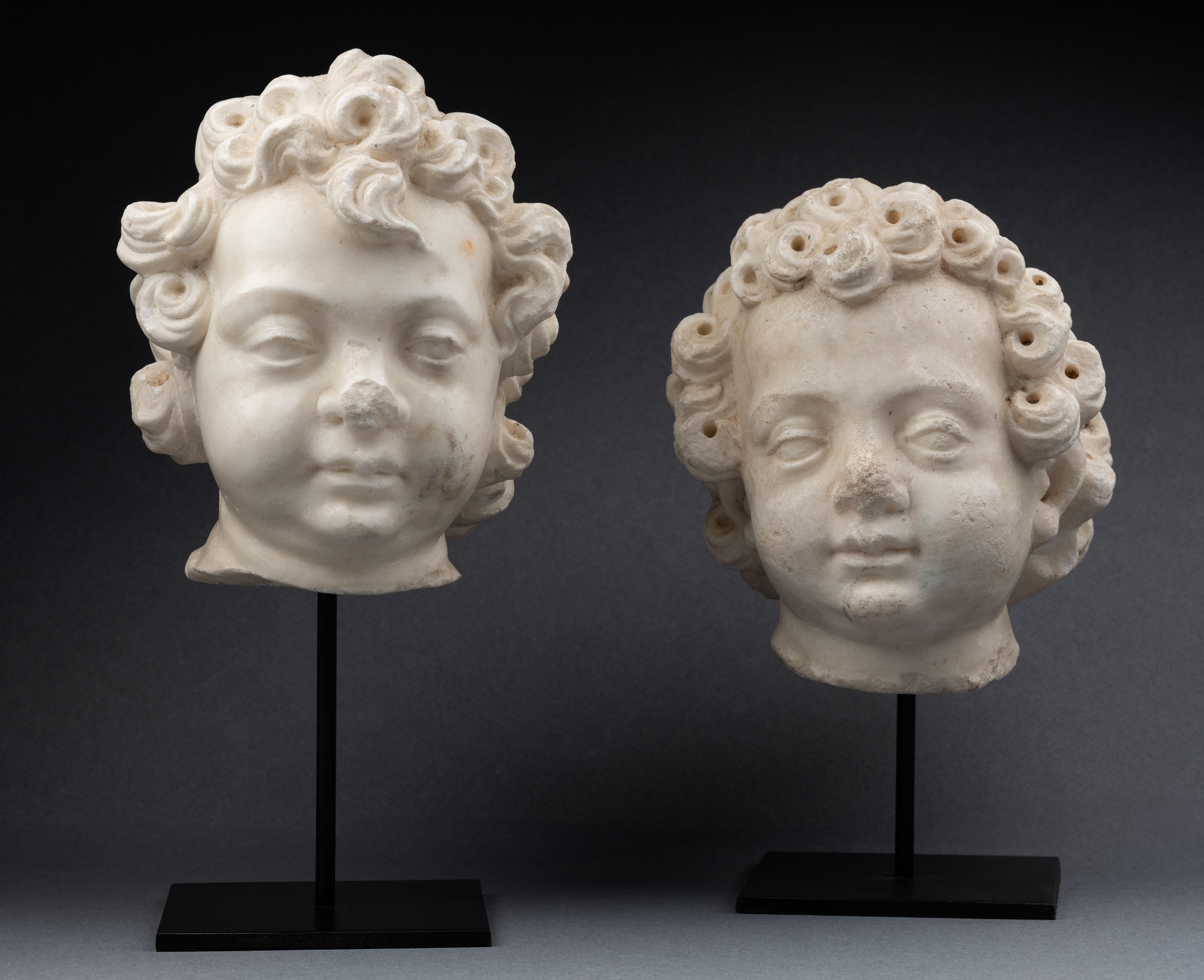 Lovely pair of heads of small cherubs carved in white Carrara marble.
The chubby faces adorned with admirable hair with abundant tight and deep curls with a quiff on the forehead.
These are elements from a large architectural ensemble.

16th