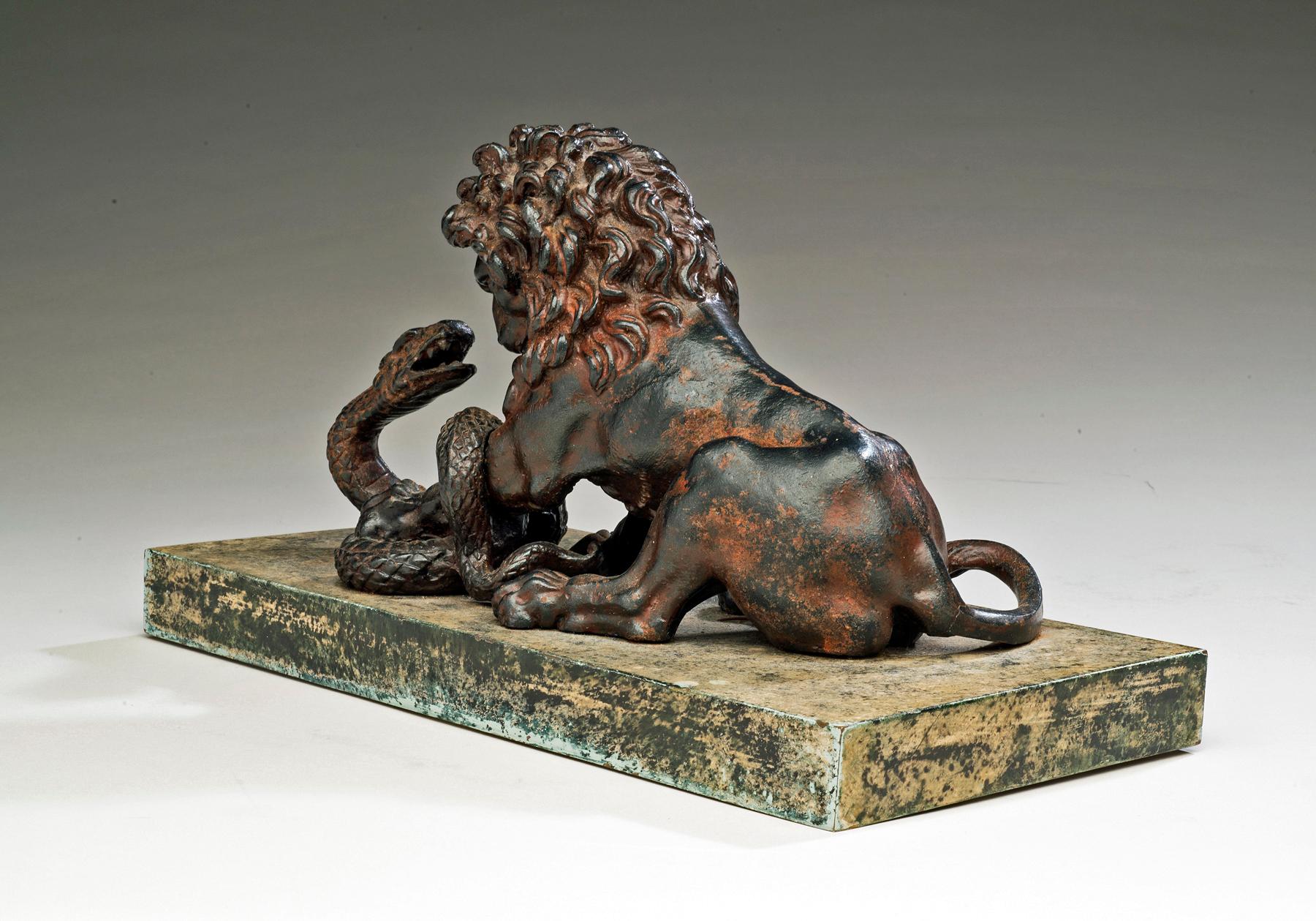 A Cast Iron Lion and Serpent Sculpture After Antoine-Louis Barye.

An impressively cast figure of a wild, roaring lion pinning a serpent to the ground; his head thrown back, jaws wide open as the reptile hisses back defiantly. Owing to the extremely