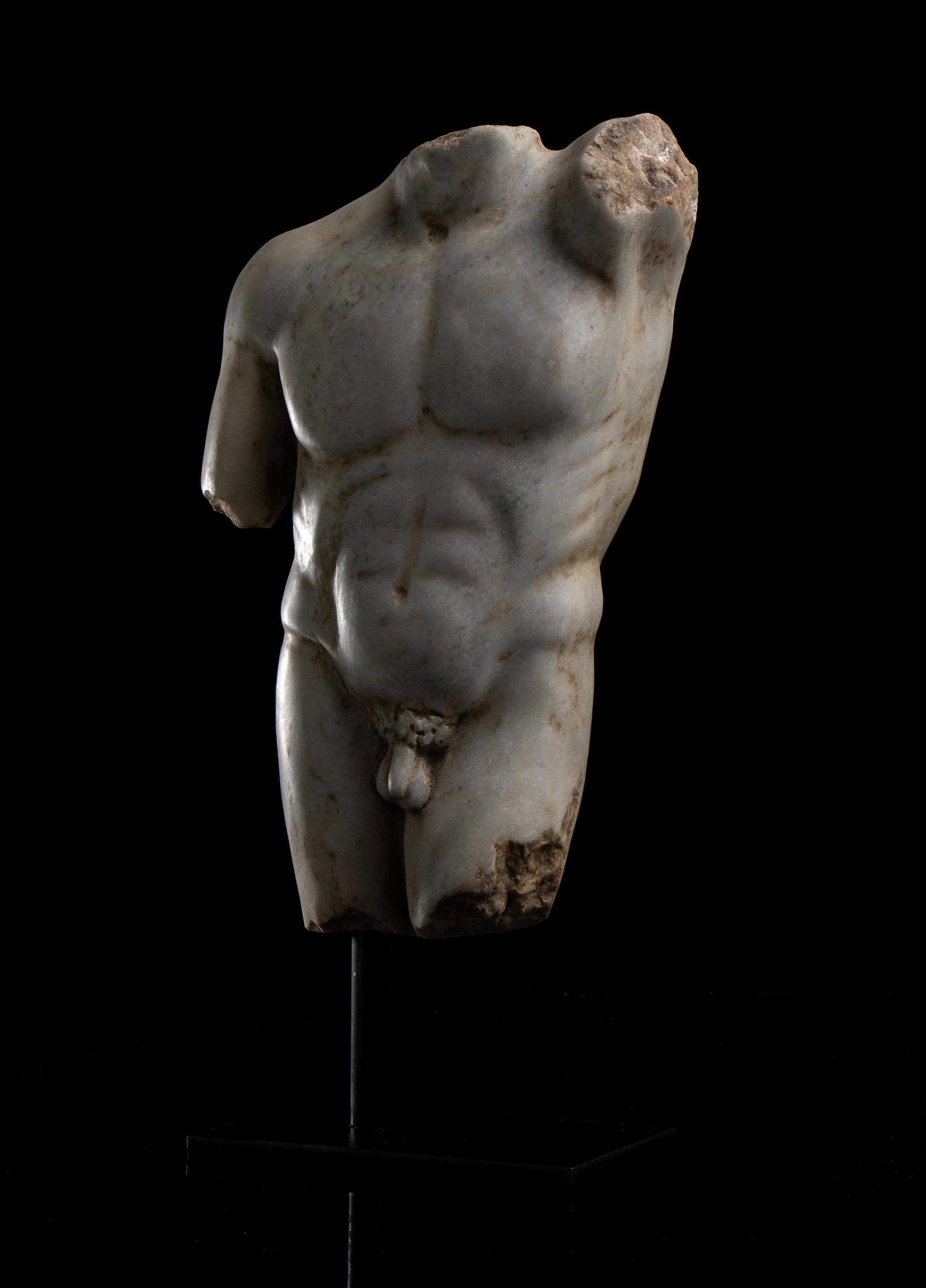 Intéressante sculpture romaine en marbre représentant le torse d'un athlète, dans le style du 1er-2e siècle après J.-C., sculptée au 19e siècle dans un atelier romain.
L'athlète se tient sur une base carrée en métal noir avec une épingle centrale