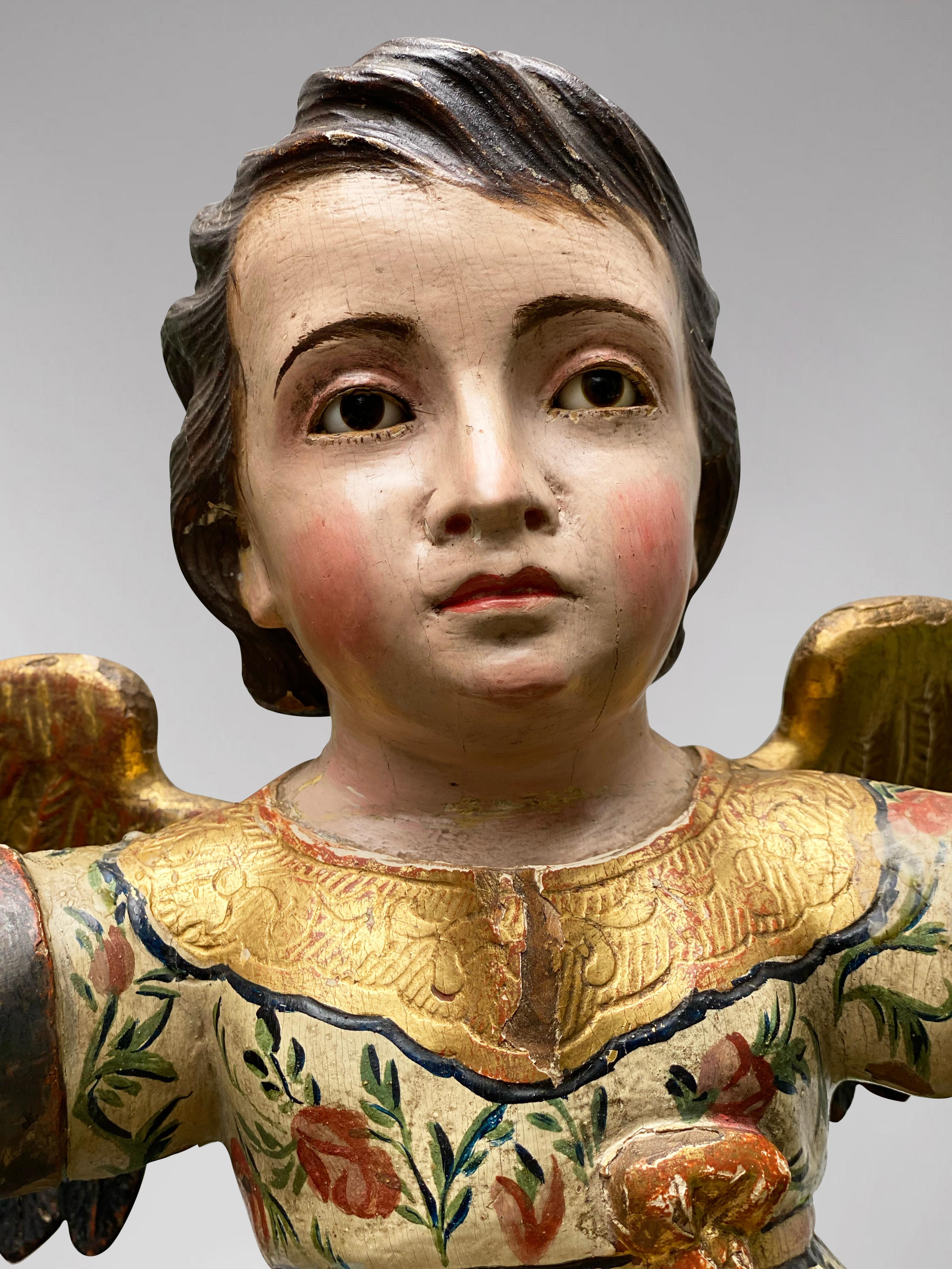 Description: A Spanish Statue of a Sitting on a Pedestal Angel with Open Arms in polychromed wood, Early 19th Century

Statue: Statue of an Angel
Object Type: Statuette
Artist, Sculptor / Maker: Unknown
Place of Origin: Spain
Period: Early 19th