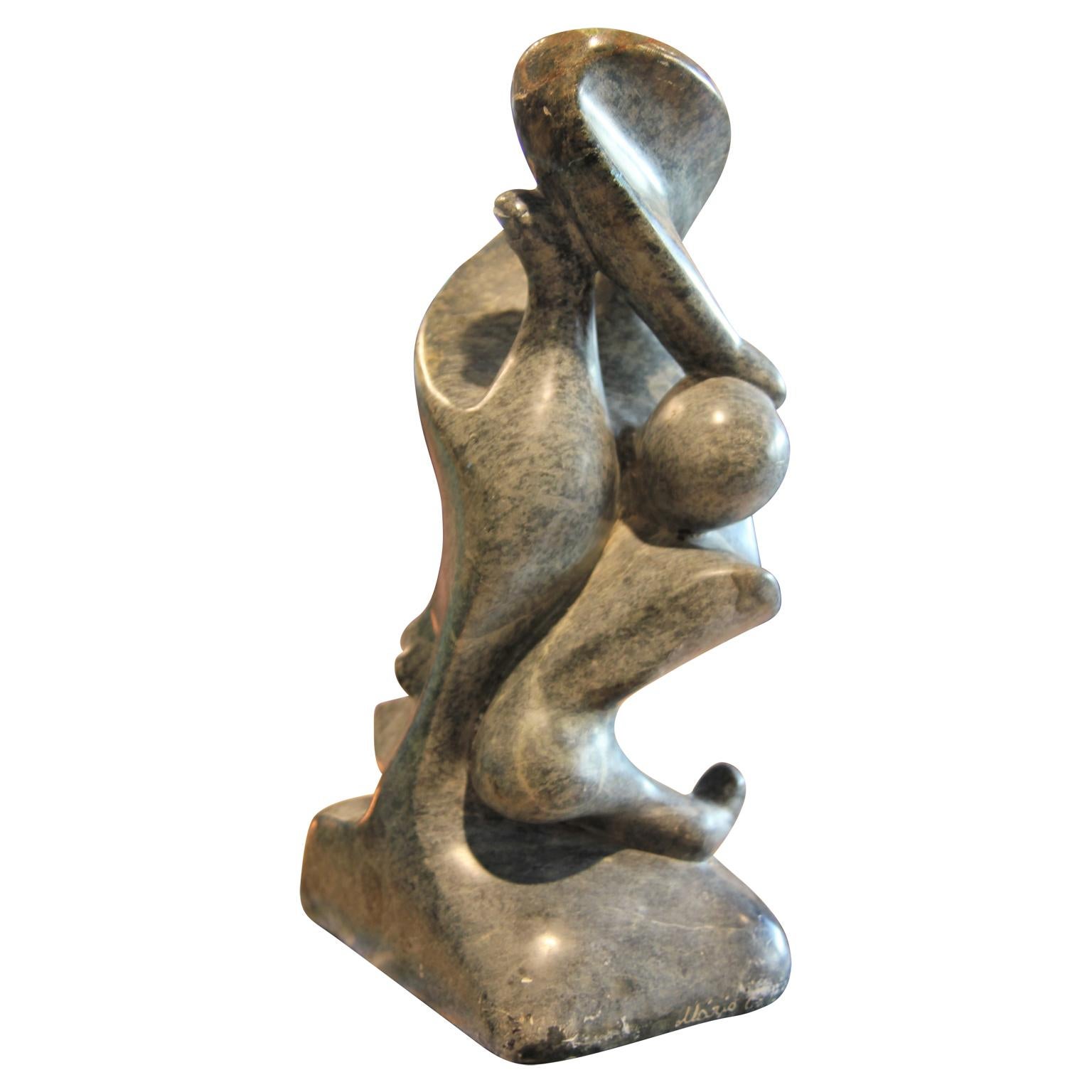 Abstract figurative grey marble sculpture that incorporates a variety of human appendages (nose, feet, and fingers). The base is signed 