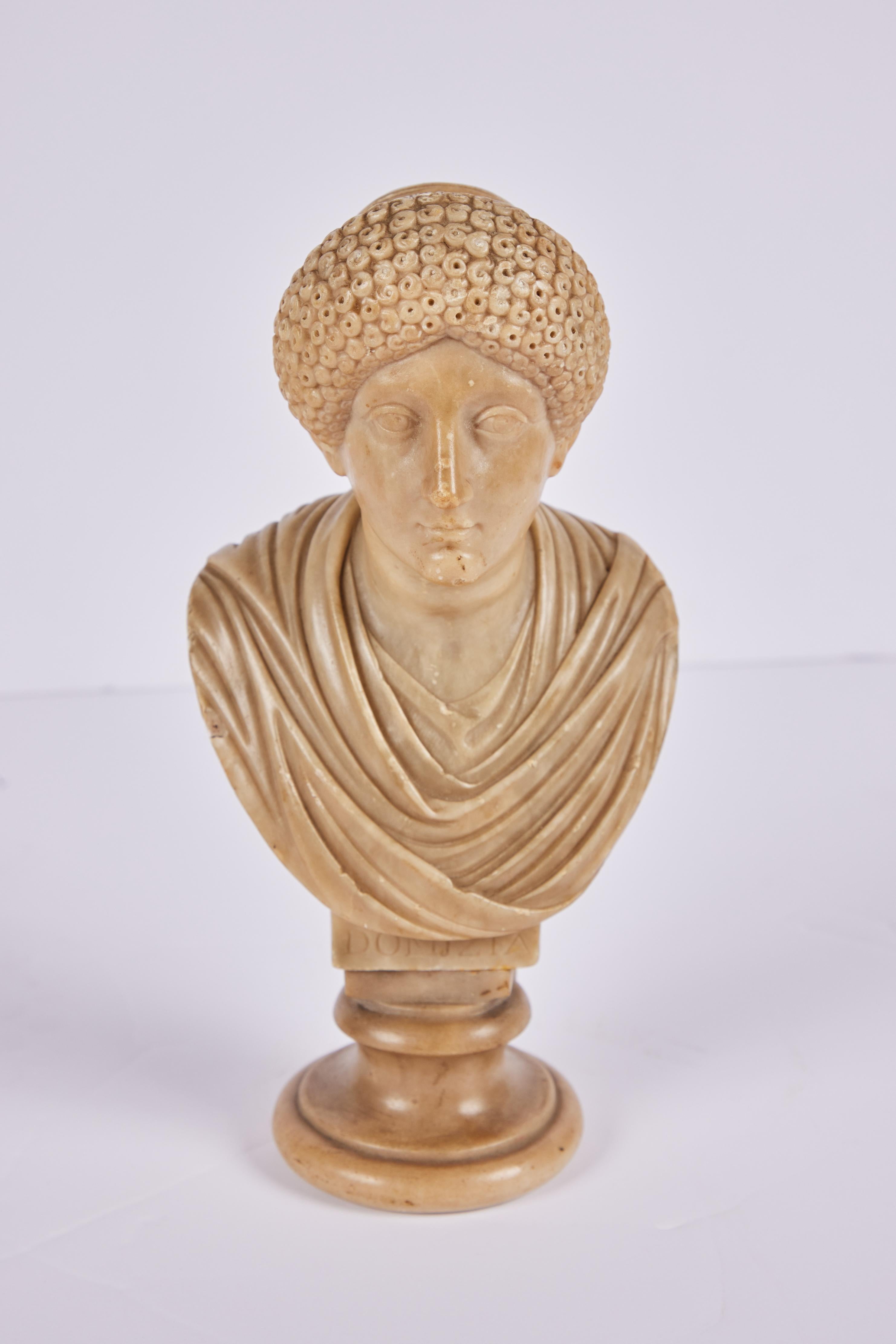 A petite 19th c. hand-carved alabaster bust of Empress Domitia Longina (c. 50-126, CE) in an elaborate hairstyle of the period. Sitting on a raised base of the same alabaster. Inscribed 