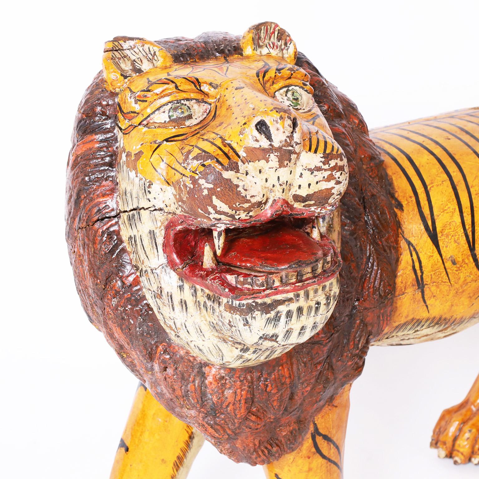 Whimsical carved mahogany rustic sculpture of a big cat with a surprising yet charming combination of the form of a lion and the stripes of a tiger. Retaining its original paint now worn to perfection.