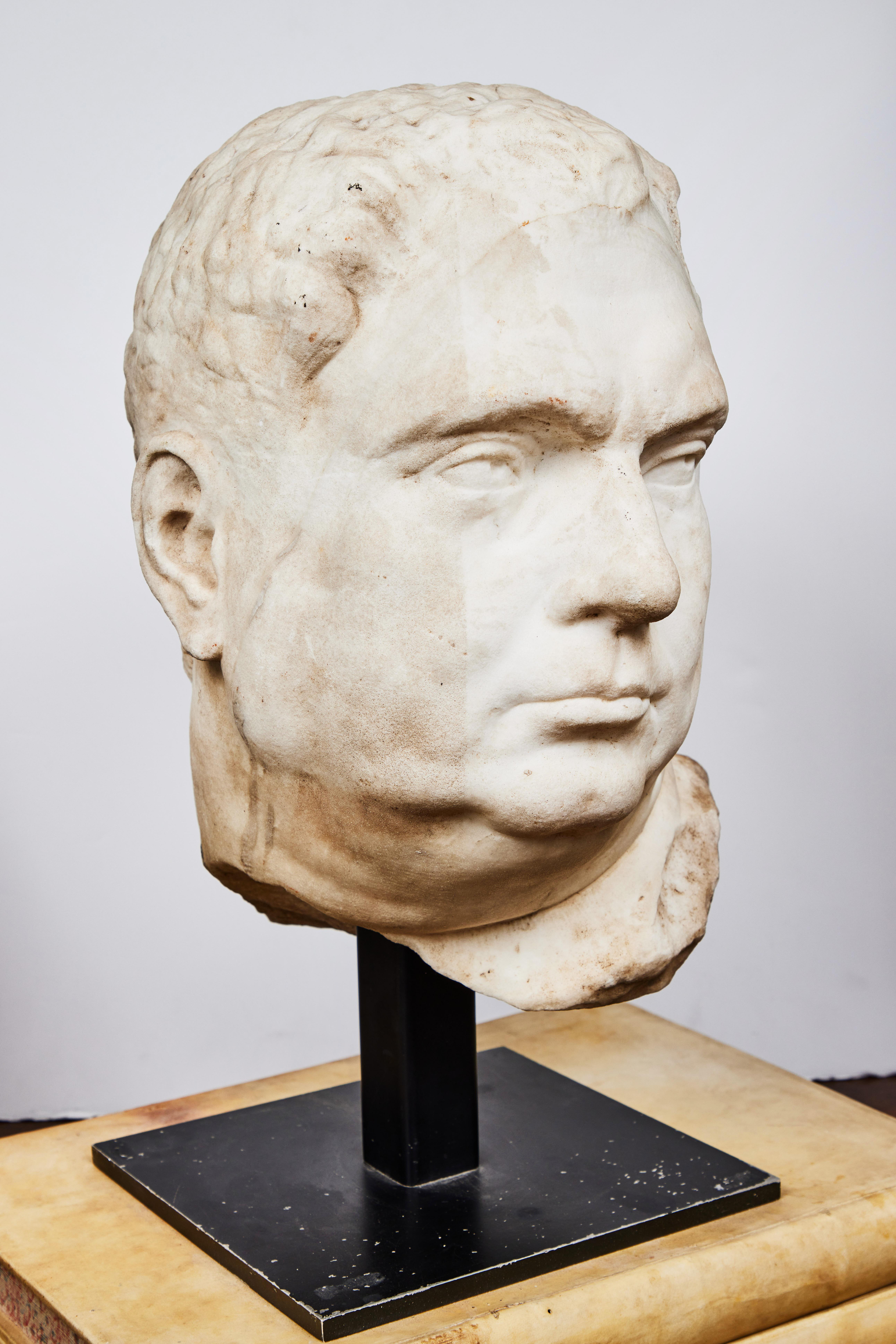 Substantial, hand carved, solid marble bust of Roman Emperor Vitellius (24-69 C.E.) on a custom, iron base. Likely a 16th century copy of a 2nd century original known as the “Grimani Vitellius”, which was gifted to Cardinal Domenico Grimani for his