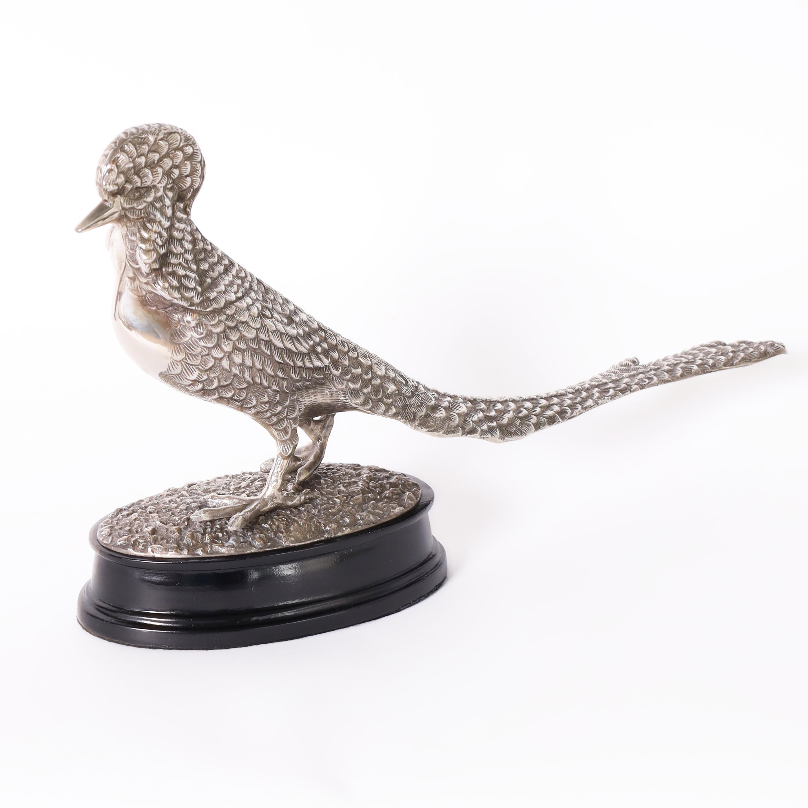 Lofty antique English pheasant figure or statuette crafted in silver plate on brass with ambitious detail and presented on a classic ebonized oval base.