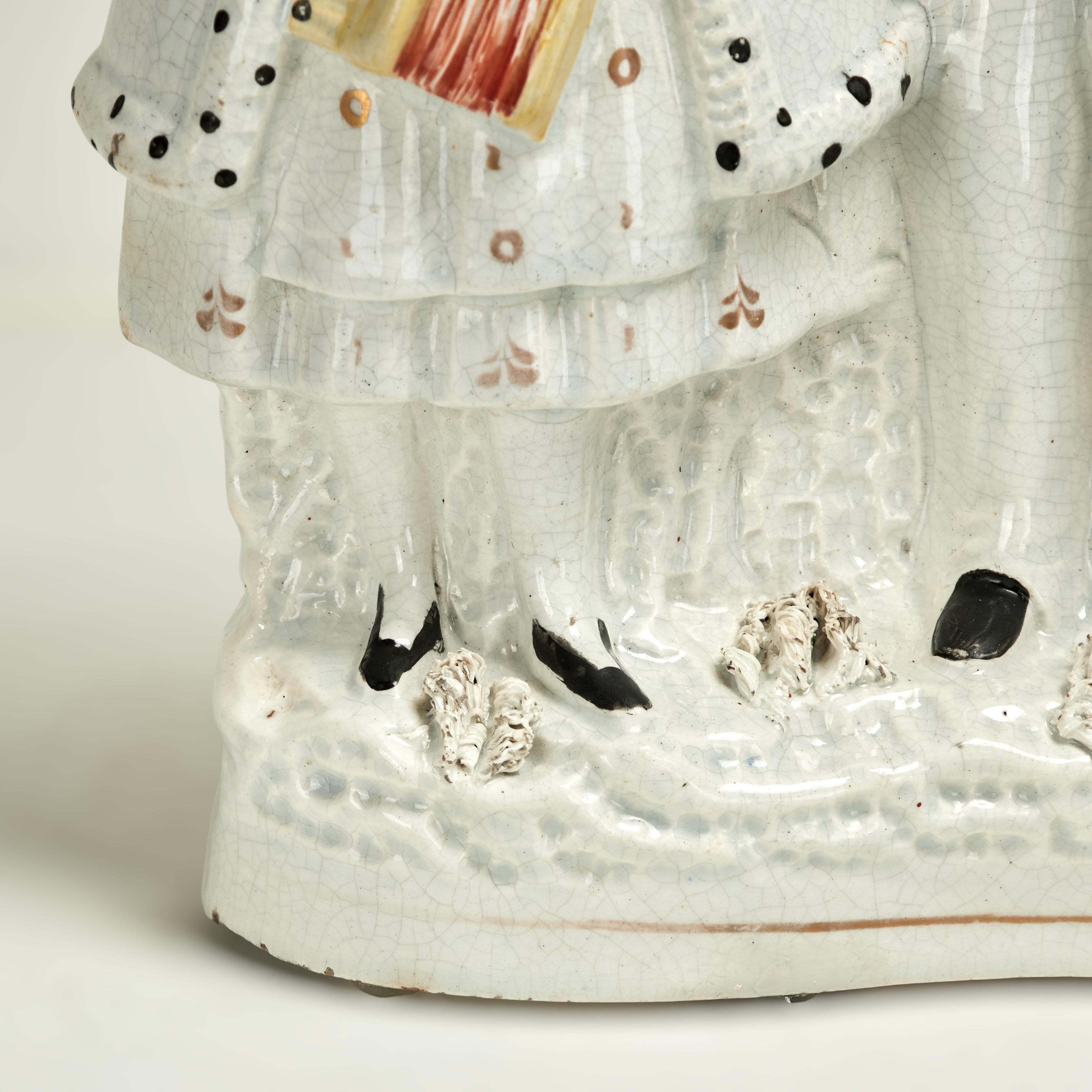 Inusuales figuras musicales inglesas de Staffordshire del siglo XIX, realizadas en porcelana y decoradas a mano, que representan una figura femenina con un acordeón y una masculina con un piano de barril.