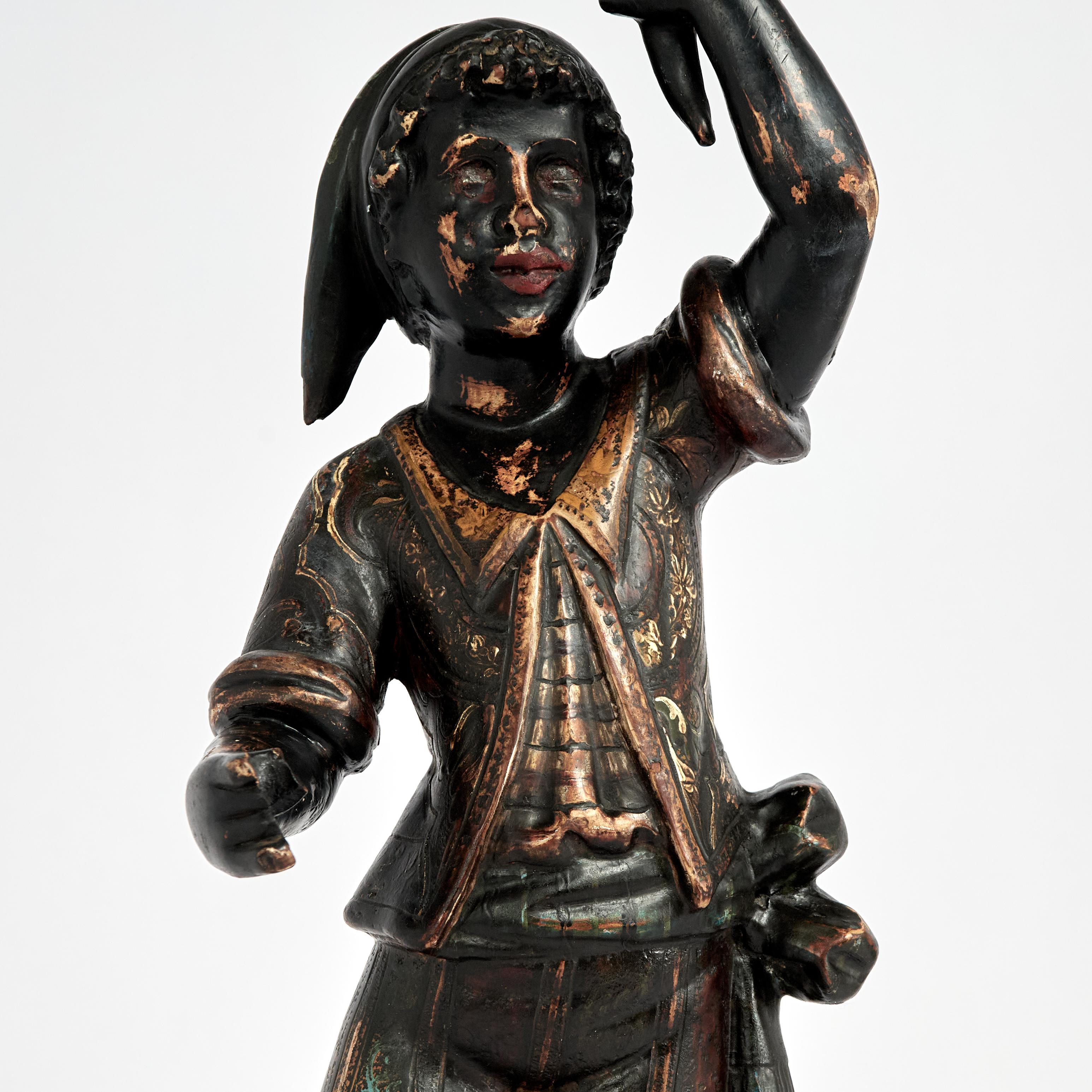 Impressionnant gondolier italien du XIXe siècle sculpté à la main dans du bois dur avec des détails réalistes, vêtu du chapeau, du gilet et de la ceinture typiques, tenant une torche et se tenant debout sur une gondole posée sur une base classique