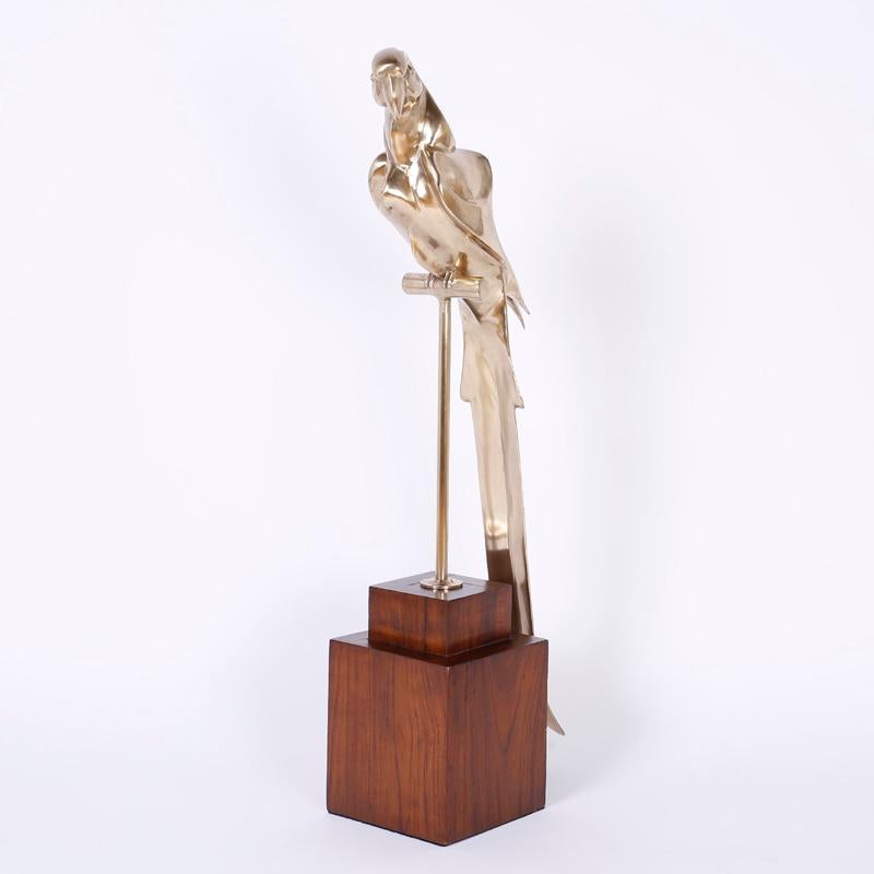 Impressive cast brass Macaw parrot sculpture crafted in the Mid-Century with Art Deco influence. Having graceful flowing form and presented on a walnut stand. Hand polished and lacquered for easy care.