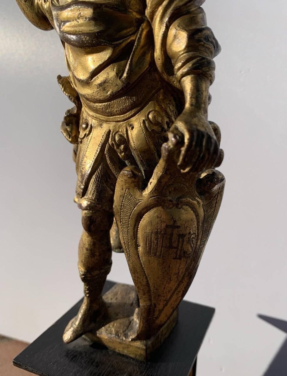 Escultura de bronce dorado - Marte, dios de la Guerra. Roma, siglo XVII.

9 x 9 x h 31 cm.

Totalmente de bronce fundido, cincelado y dorado, descansa sobre un pedestal de madera ebonizada decorado con cuatro placas de bronce dorado que representan