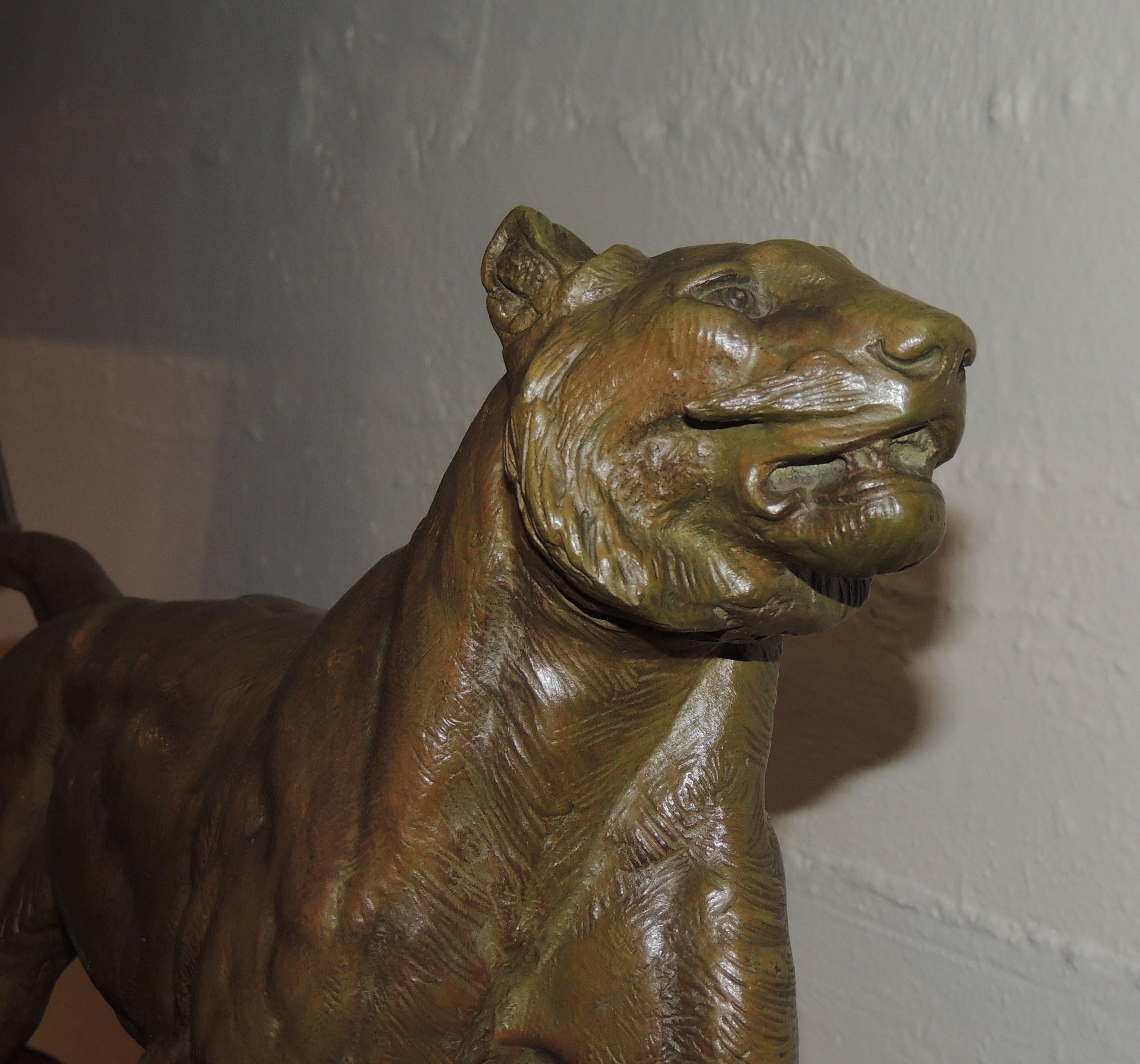 Es handelt sich um eine Art-Deco-Bronzestatue eines Löwen mit einem großen, dreifarbigen Marmorsockel, in den geometrische Formen eingelegt sind. Der Löwe ist kraftvoll dargestellt, und sein Ausdruck und seine Muskulatur sind gut ausgeprägt.

Im