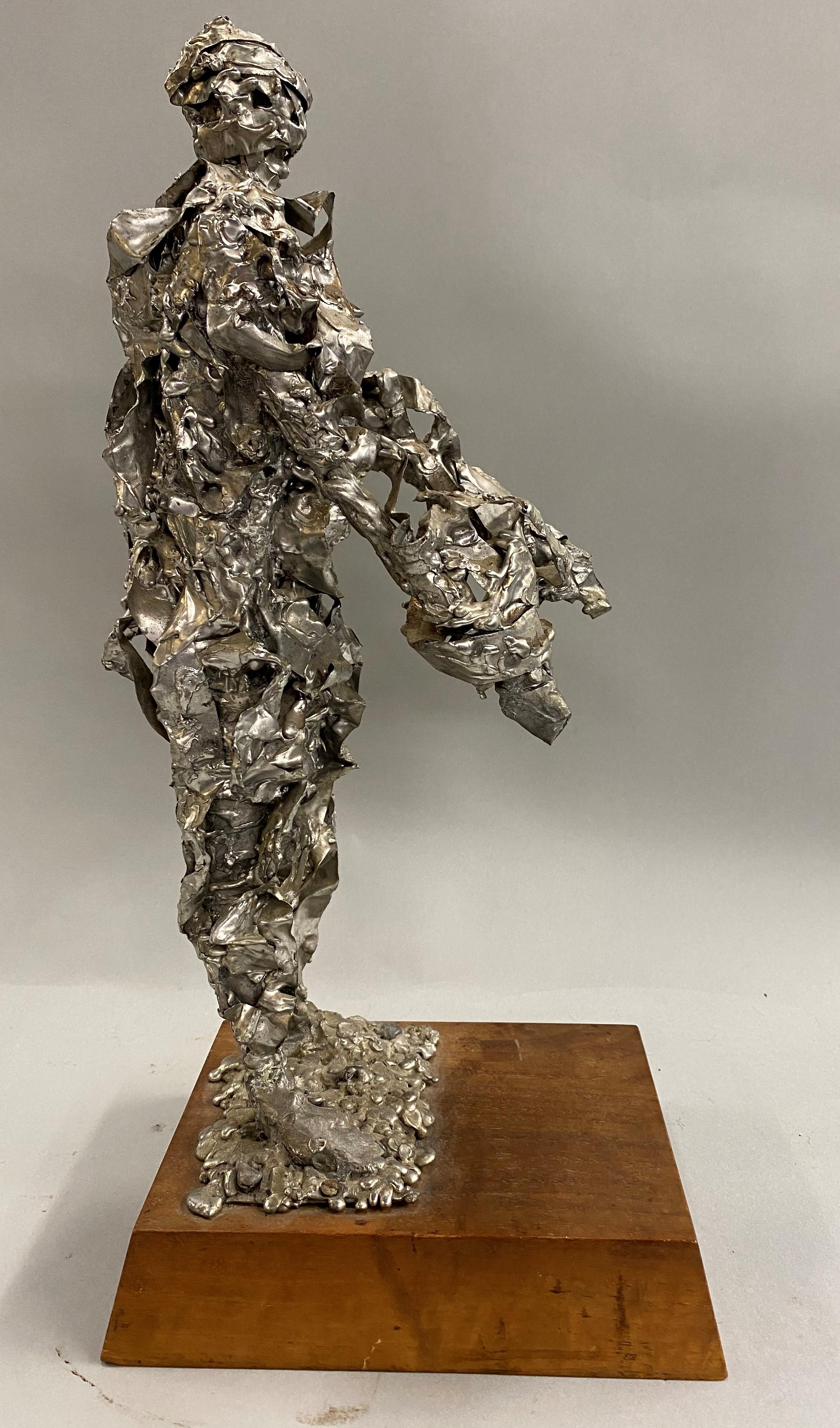 A fine modern mid century brutalist sculpture of a man with arms extended forward, in silver plated heavy metal, probably lead or bronze, unsigned, and mounted on a dimensional museum style wooden base, with minor staining in spots Provenance: