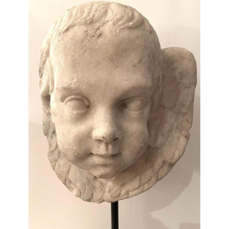 Hand carved Carrara  marble head of a cherub's face surrounded by wings.  Later mounted on metal base.
