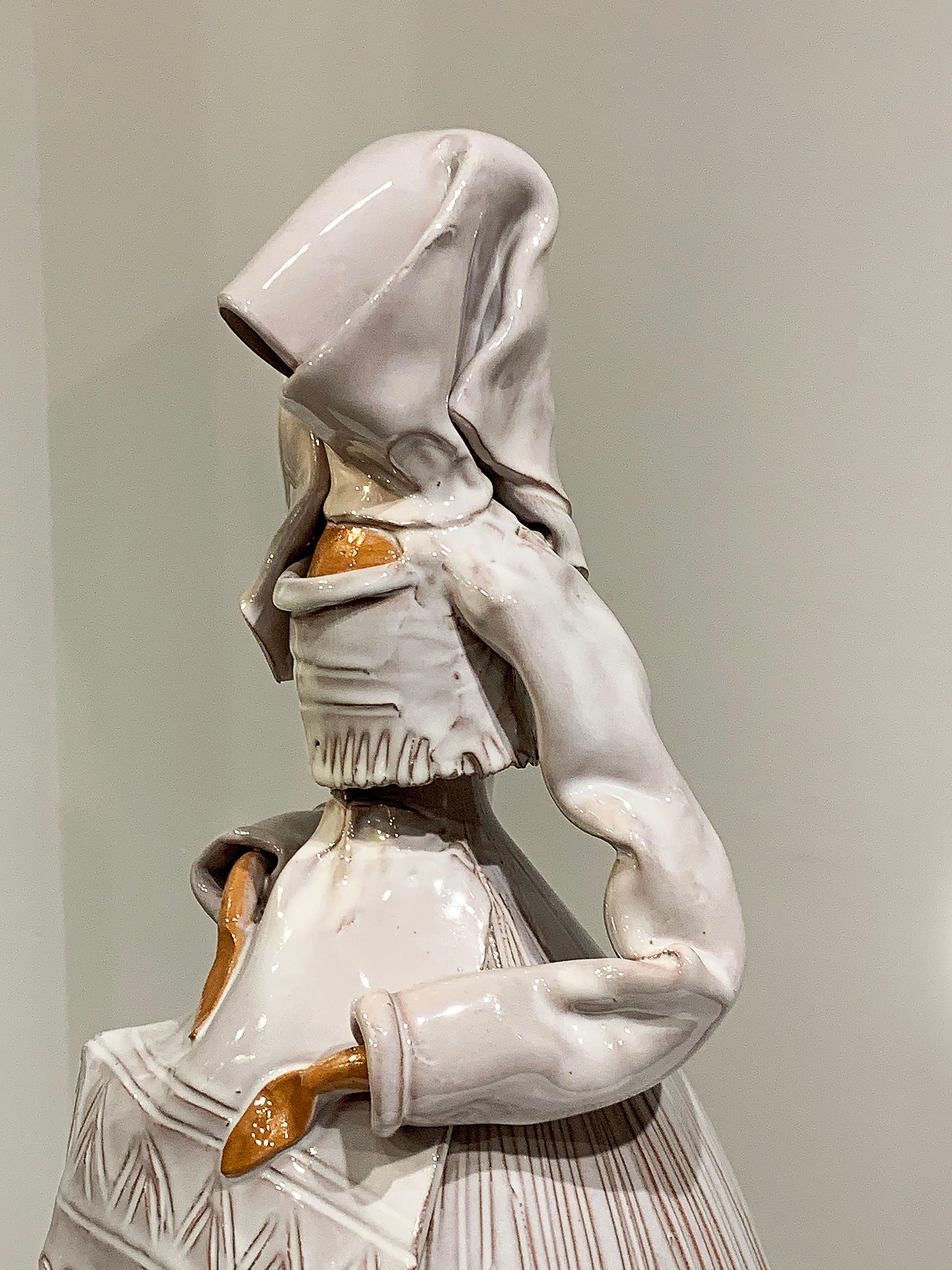 Veiled ceramic female sculpture. This sculpture is meticulously done and her look is very intriguing. The dress she wears appears to flow as she walks and much care was taken to make the ceramic look like textile. Her head is hidden behind the veil,