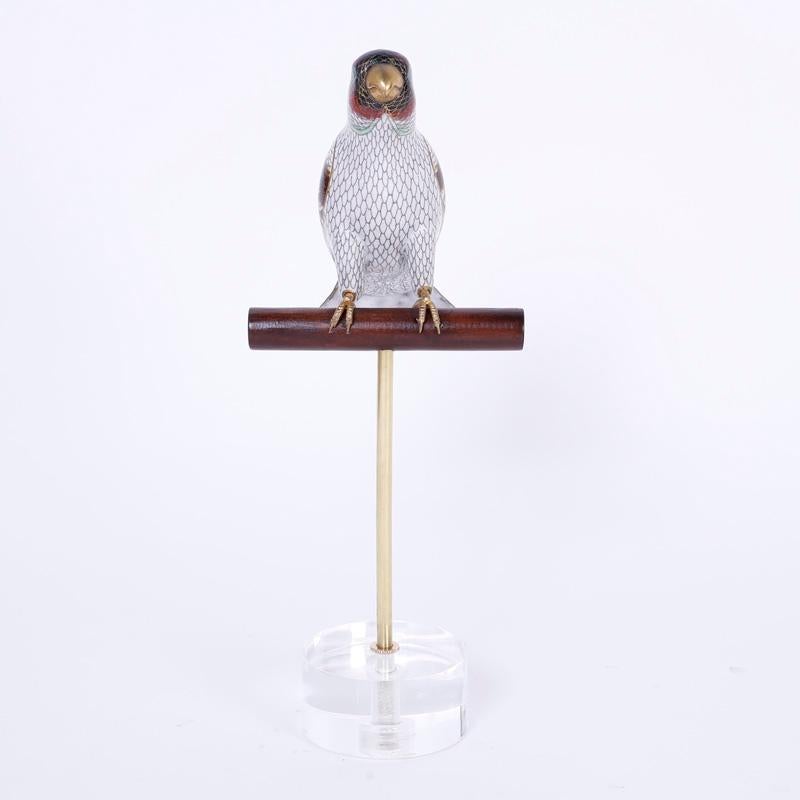 Raffinato pappagallo o uccello cinese sapientemente decorato con smalto su ottone, presentato su un trespolo in legno personalizzato e un supporto in lucite.