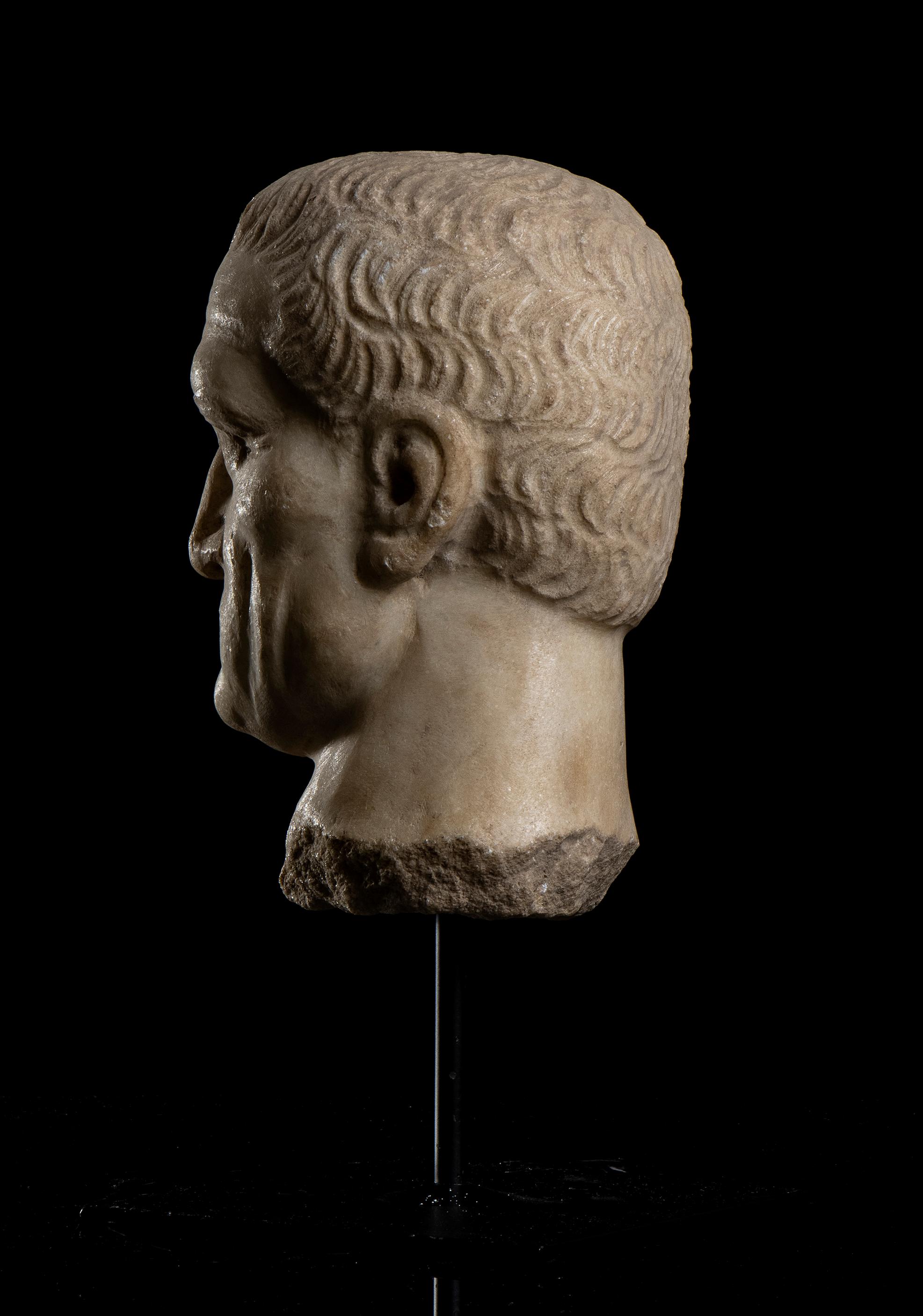 A classical roman archeological style, sculpture head depicting Emperor Maximinus Thrax;  the head standing on a pin centered on a square metal base carved in an aged statuary marble in central Italy probably in Rome in first half of XX century.